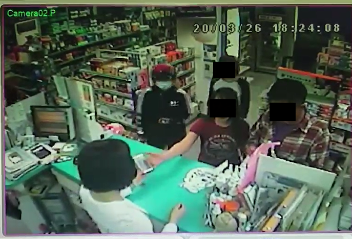 紅衣女子（中）將手機交給藥師，聲稱要用戶口名簿領取口罩。（讀者提供）