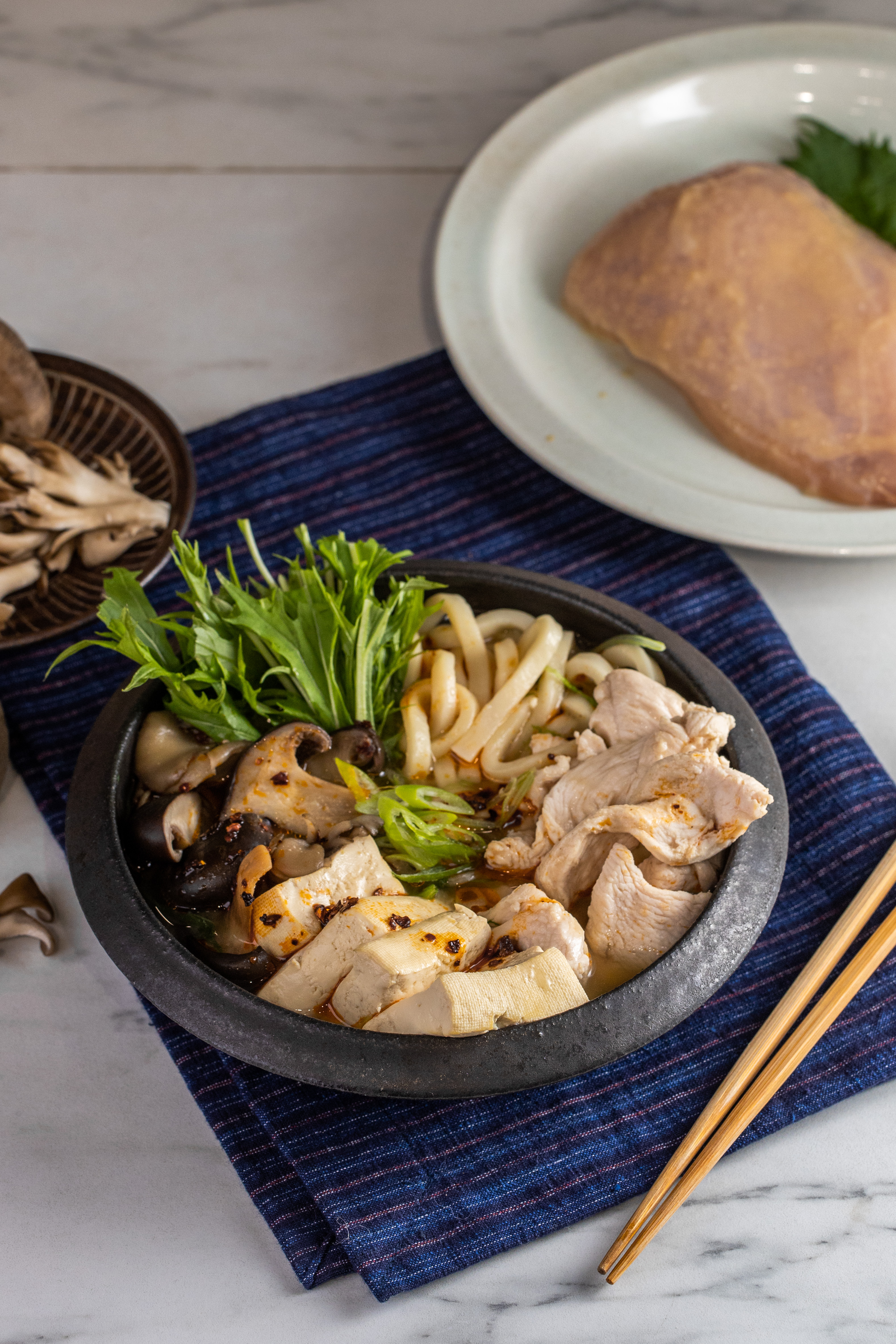 「白味噌雞胸烏龍麵火鍋」選用甘口白味噌帶出溫潤甜味，雞胸肉煮熟即熄火，搭配爽脆水菜是一絕。（雞胸145元／包）