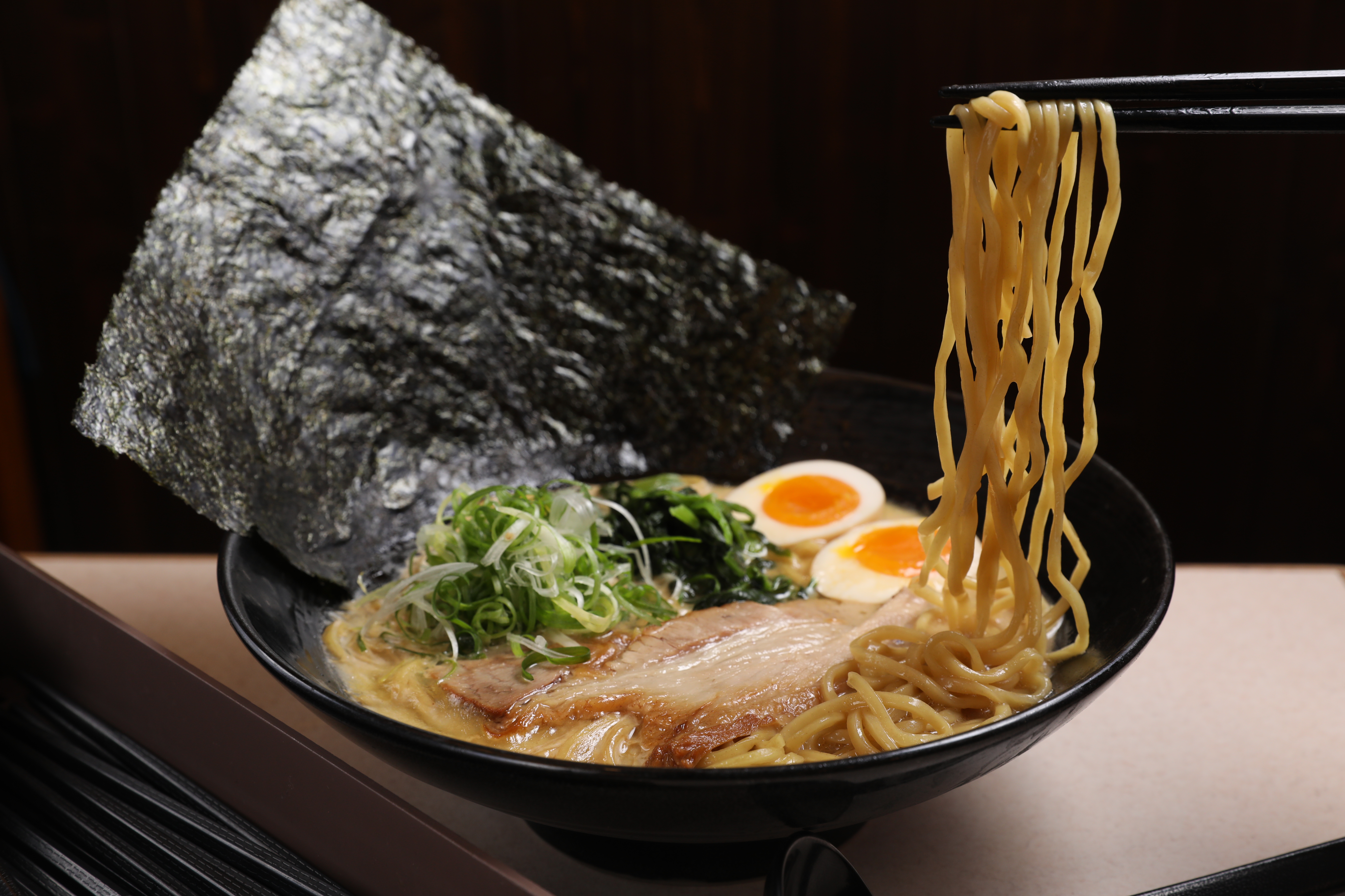 「味玉豚骨醬油拉麵」湯頭甘醇，五花叉燒油潤豐腴，菠菜解膩，海苔能撕成小片沾湯再與麵條一起入口。（220元／碗）
