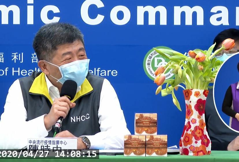 陳時中秀出鬱金香與荷蘭焦糖煎餅，卻不小心說成「玫瑰花」，被指正後露出靦腆的笑容。（翻攝自衛生福利部疾病管制署記者會畫面）
