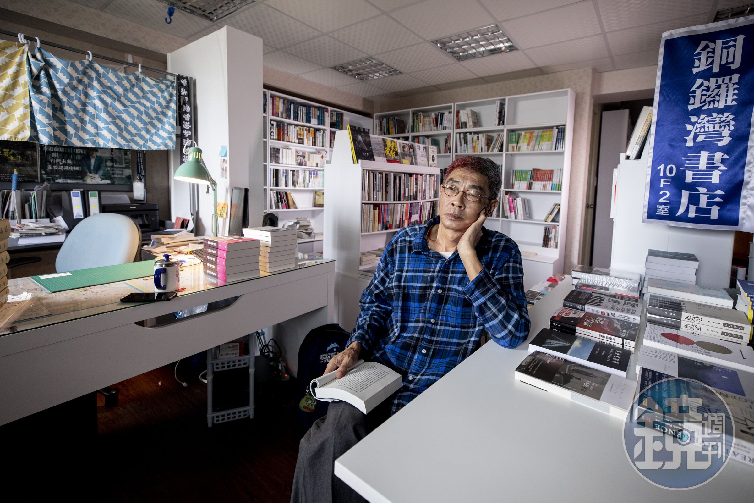 開幕前夕，林榮基坐在群書環繞的小書店中，若有所思。這裡也是他的住所，左方布簾後方就是他的睡床。