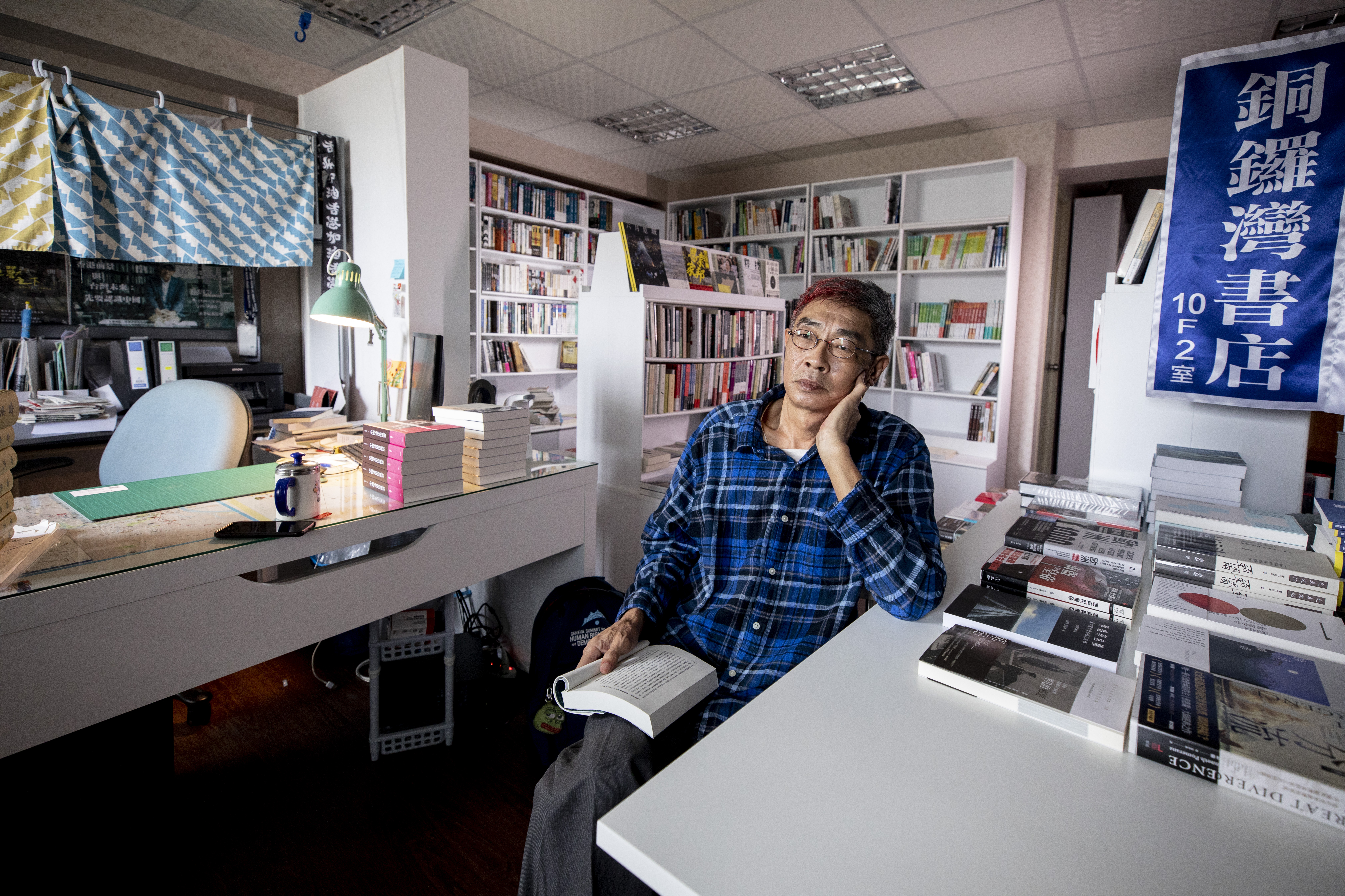 開幕前夕，林榮基坐在群書環繞的小書店中，若有所思。這裡也是他的住所，左方布簾後方就是他的睡床。