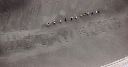 知名觀光勝地湘南海岸居民在海灘上寫下「#STAYHOME」。(翻攝自共同通信社)