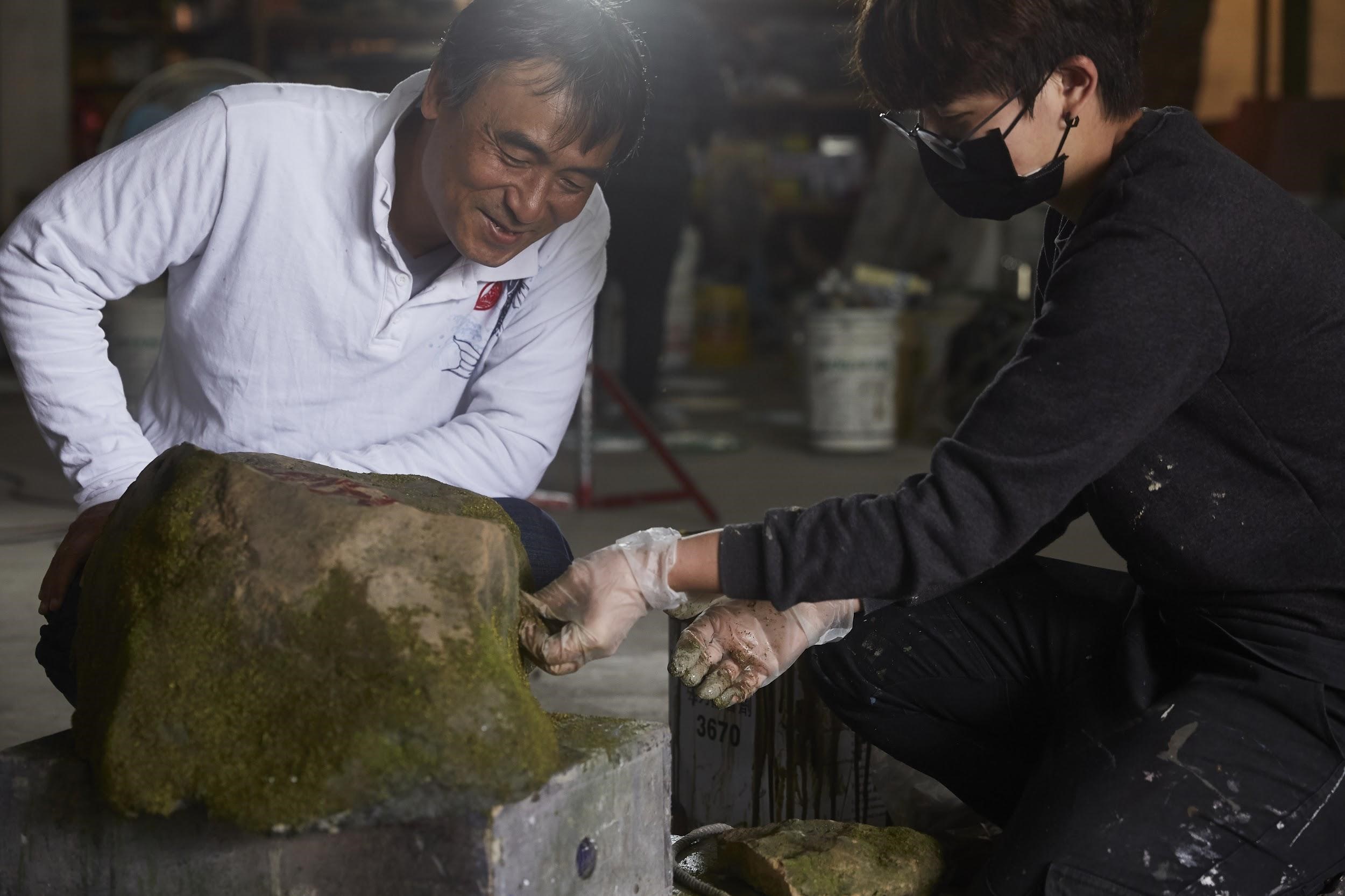 陳新發在工作現場指導質感團隊成員如何在「石頭」上製造「青苔」。