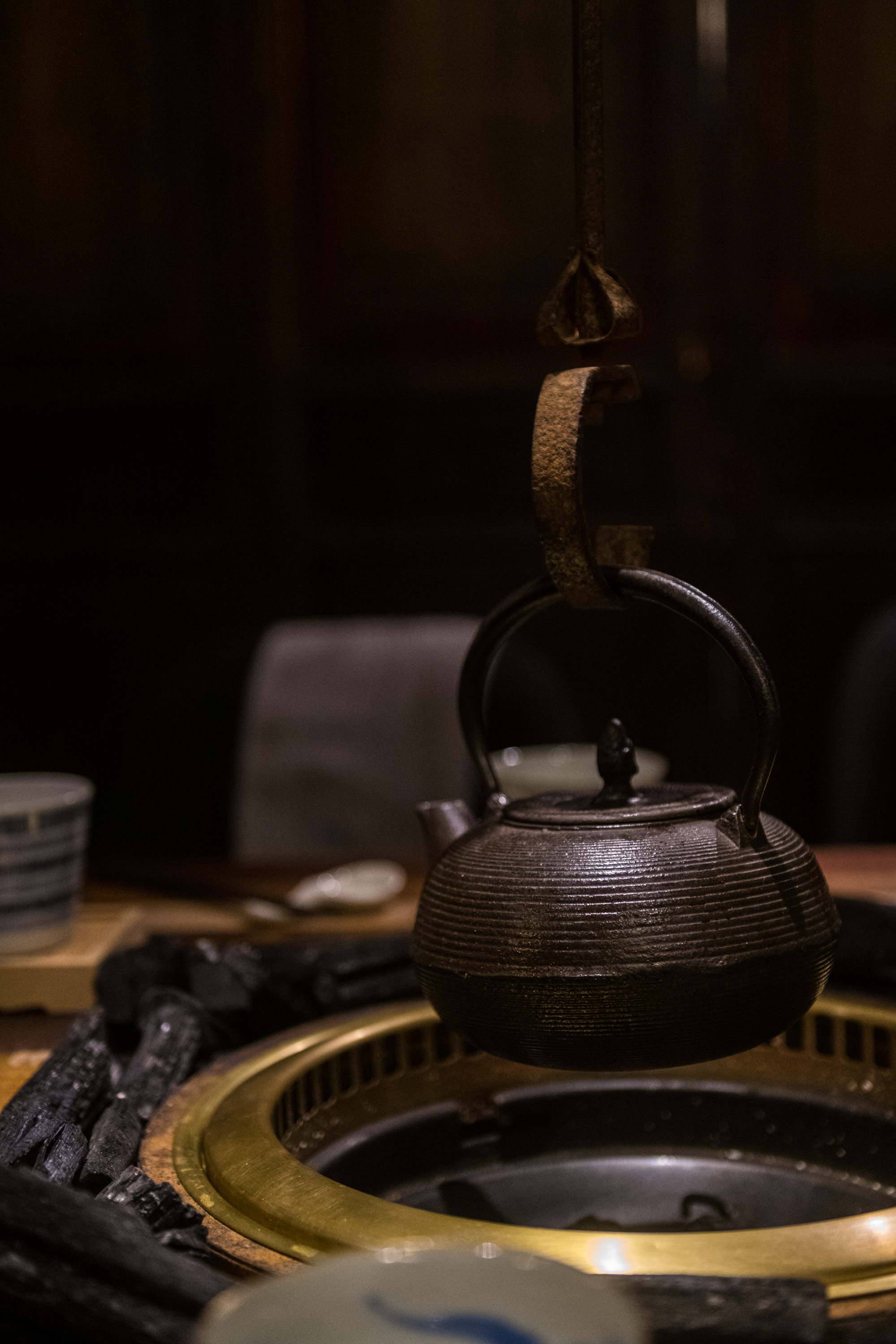 座位區以日本傳統地爐的概念作設計，但將高度拉到餐桌上，懸在半空的鐵壺，底下是用木炭加熱，熱煙從壺嘴噴出，有種暖意。