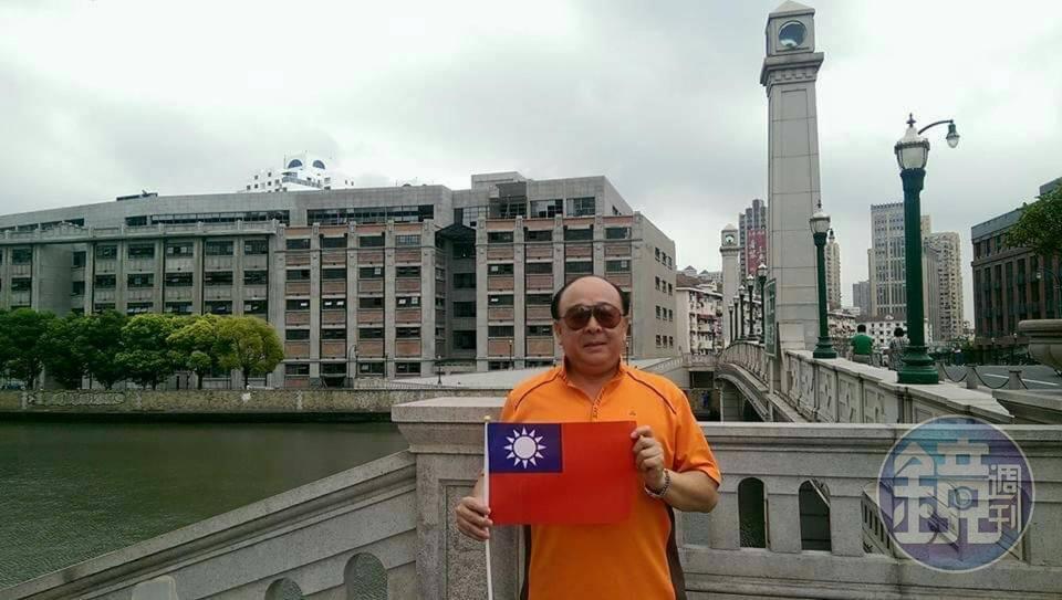 吳斯懷說旅遊時都會攜帶國旗,他曾赴四行倉庫,攤開隨身攜帶的小國旗,請大陸民眾幫他拍照。(吳斯懷提供)