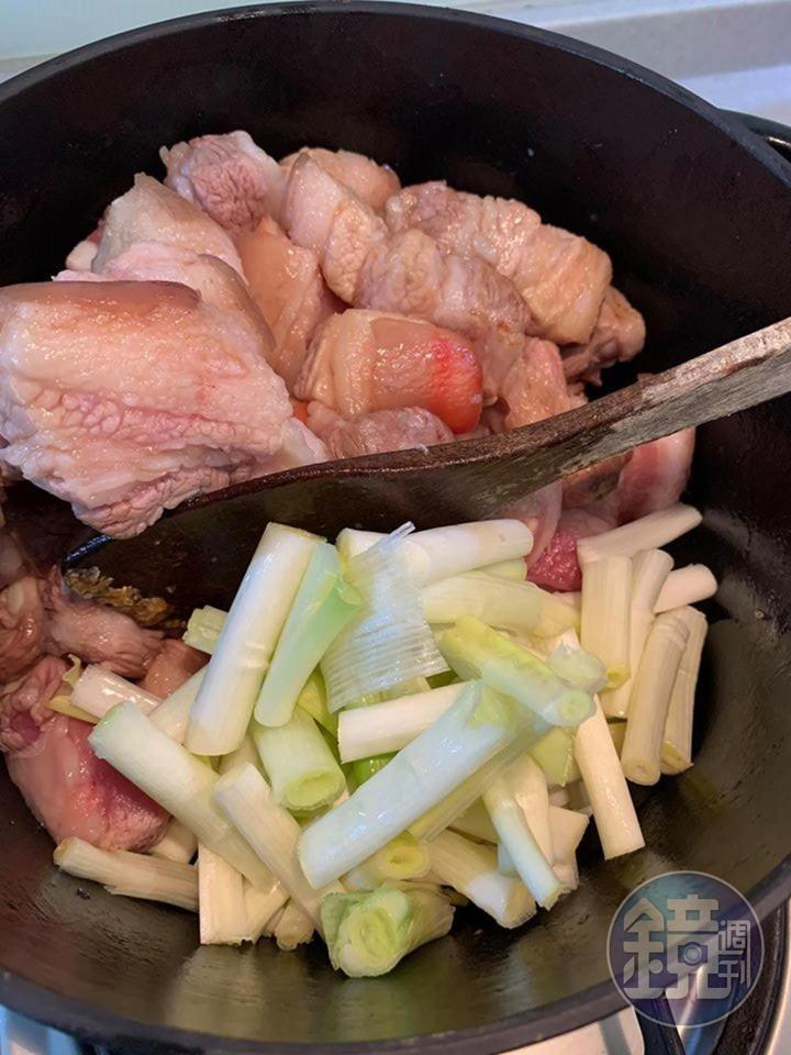等五花肉出油後,放入蔥段。