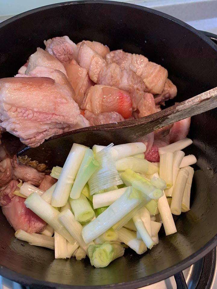 等五花肉出油後,放入蔥段。