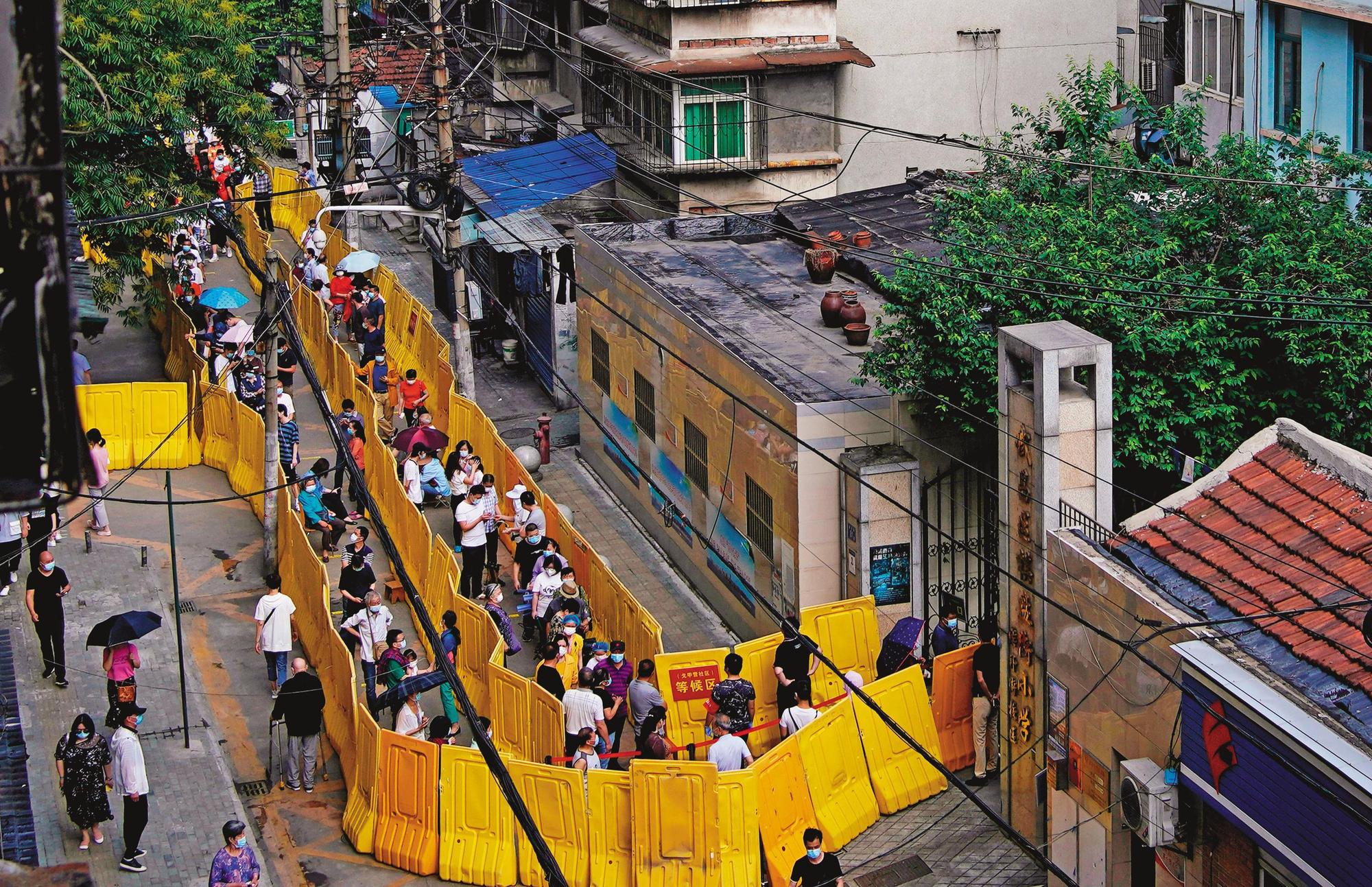 中國武漢近期又出現群聚感染,當地市政府啟動「10天大會戰」,要求10天內完成居民篩檢,武漢居民大排長龍接受採檢。(達志影像)