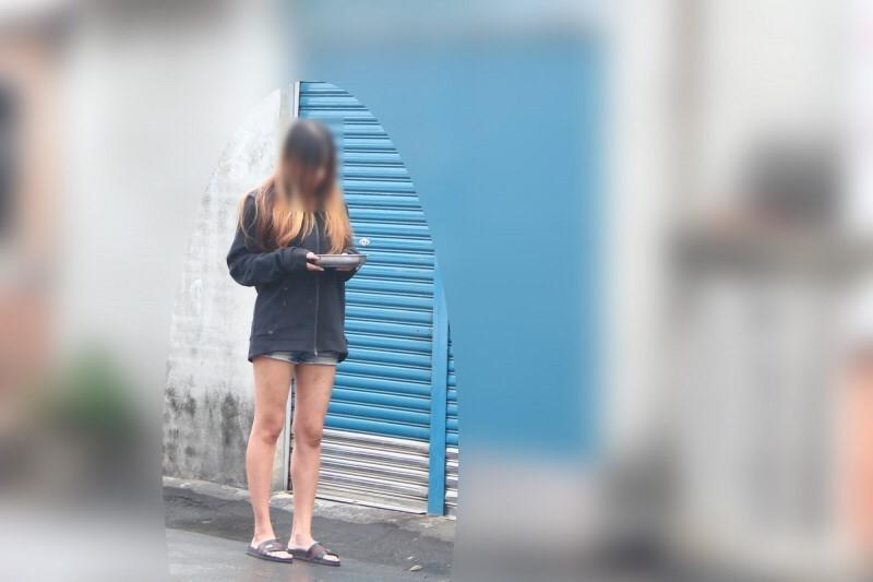 雲林沿海地區一名嫩妻手捧檳榔香菸供路人取用,疑因劈腿遭到夫家「洗門風」處罰。(讀者提供)