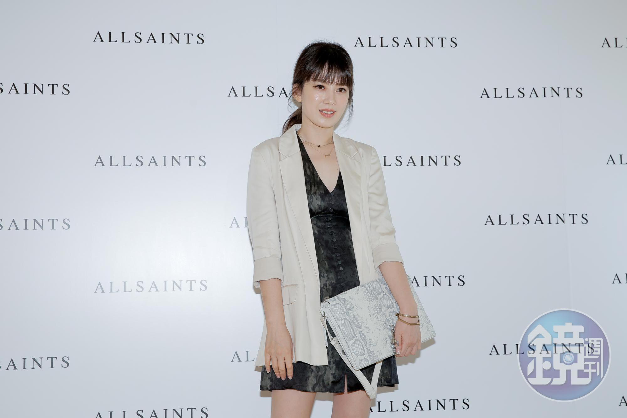 Melody穿著ALLSAINTS米白色西裝外套NT$8,900、墨綠色印花短洋裝NT$7,200、白色蛇紋壓紋斜背包NT$12,900。