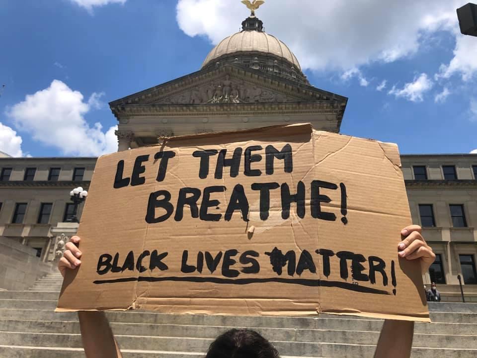 美國非裔男子佛洛伊德遭警壓頸致死,抗議民眾高舉「LET THEM BREATHE!」標語。(翻攝自16 WAPT News臉書)