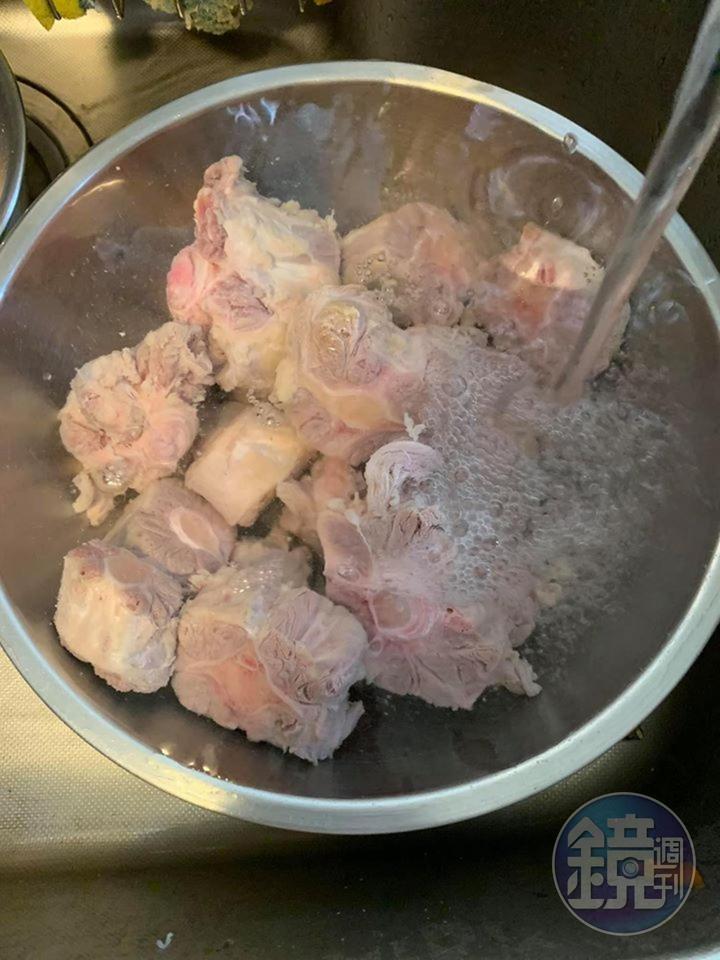 用冷水沖洗汆燙過的牛尾。
