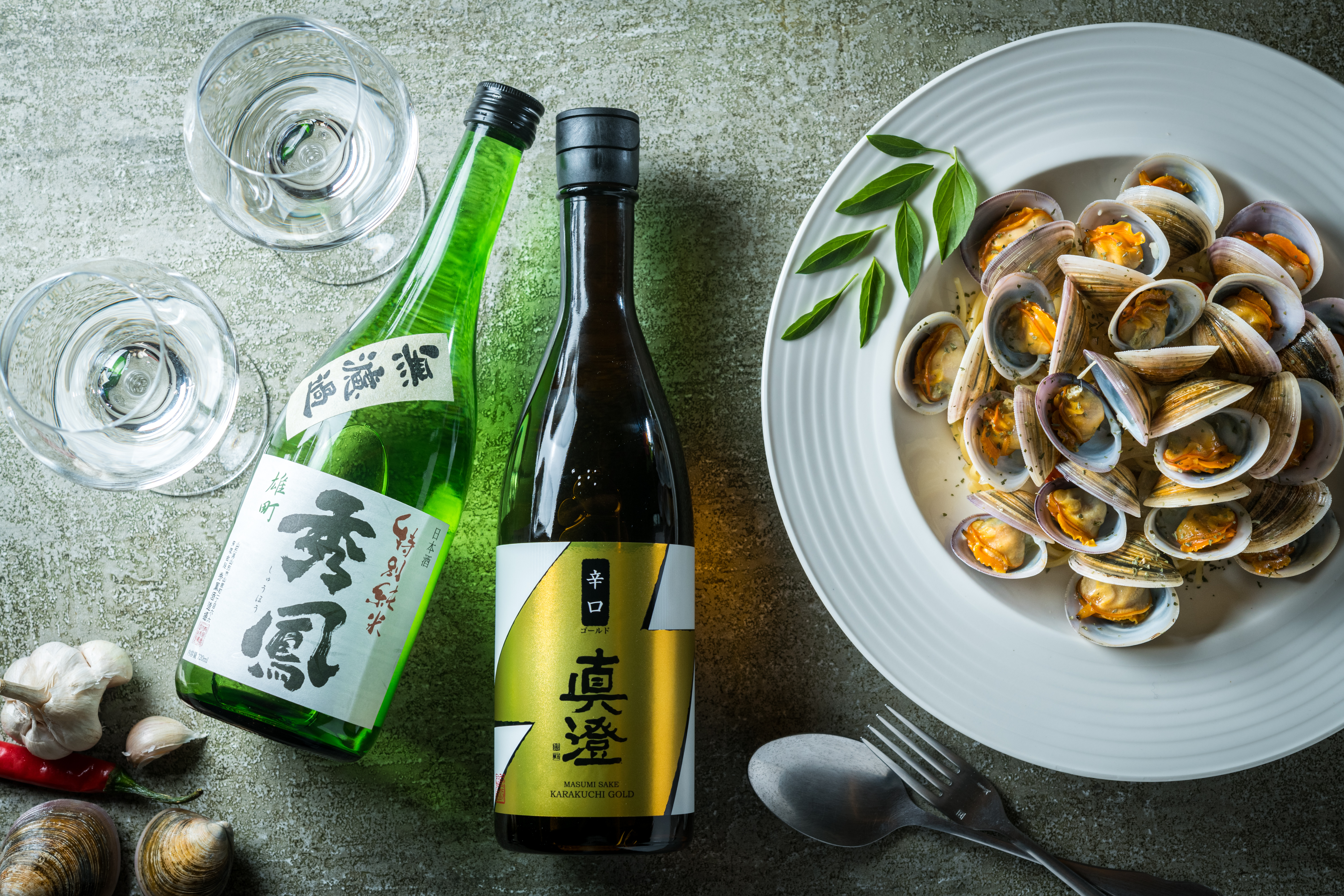 秀鳳酒造的「雄町 無濾過 特別純米酒」華美穩重（左，1,200元／720ml、瓶），真澄酒造的「辛口金標」則清麗易飲（中，830元／720ml、瓶），與鮮到爆炸的「白酒赤嘴義大利麵」（右，無菜單料理菜色）都是絕配。