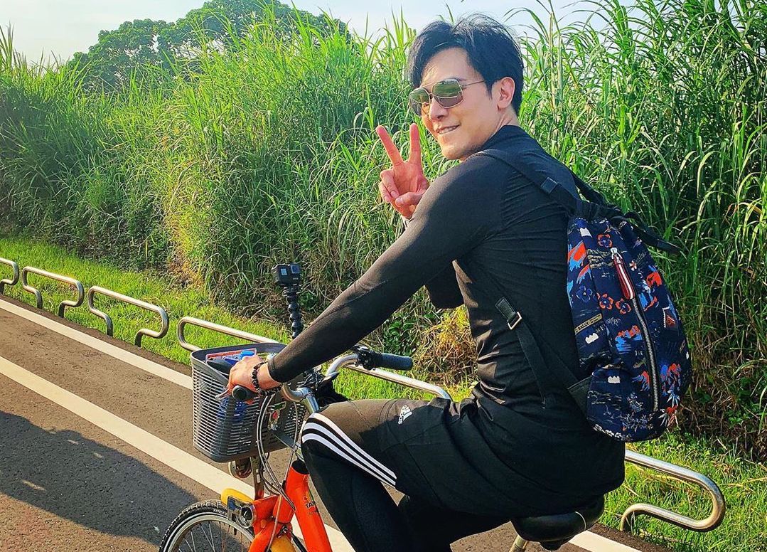 謝佳見選用EXPLORE系列深藍色尼龍彩色圖騰後背包陪他騎乘單車探索台北。（美之心提供）