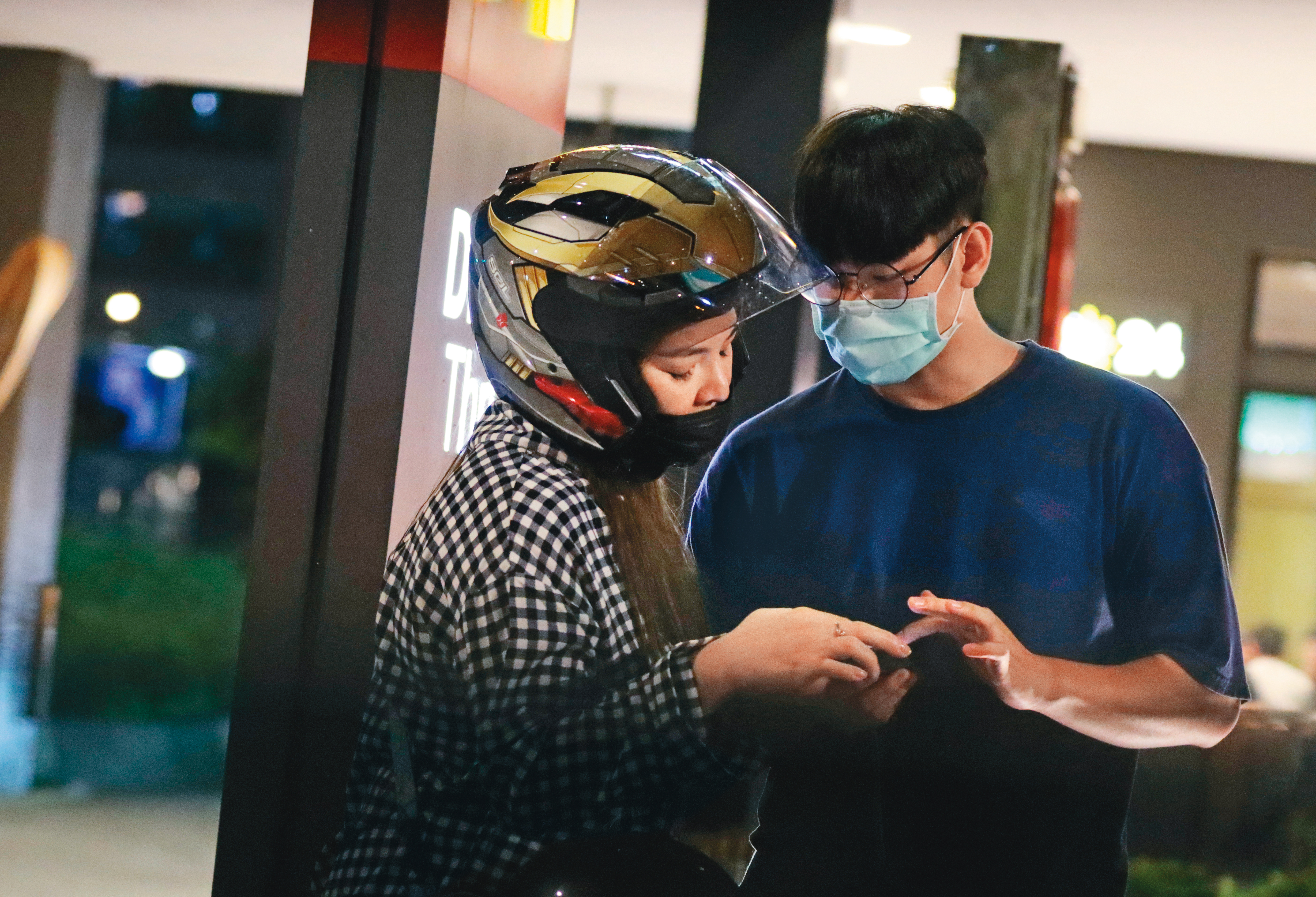 5/31 23:01，準備到速食店買宵夜前，小甜甜戴著安全帽也要跟男友一起看手機。