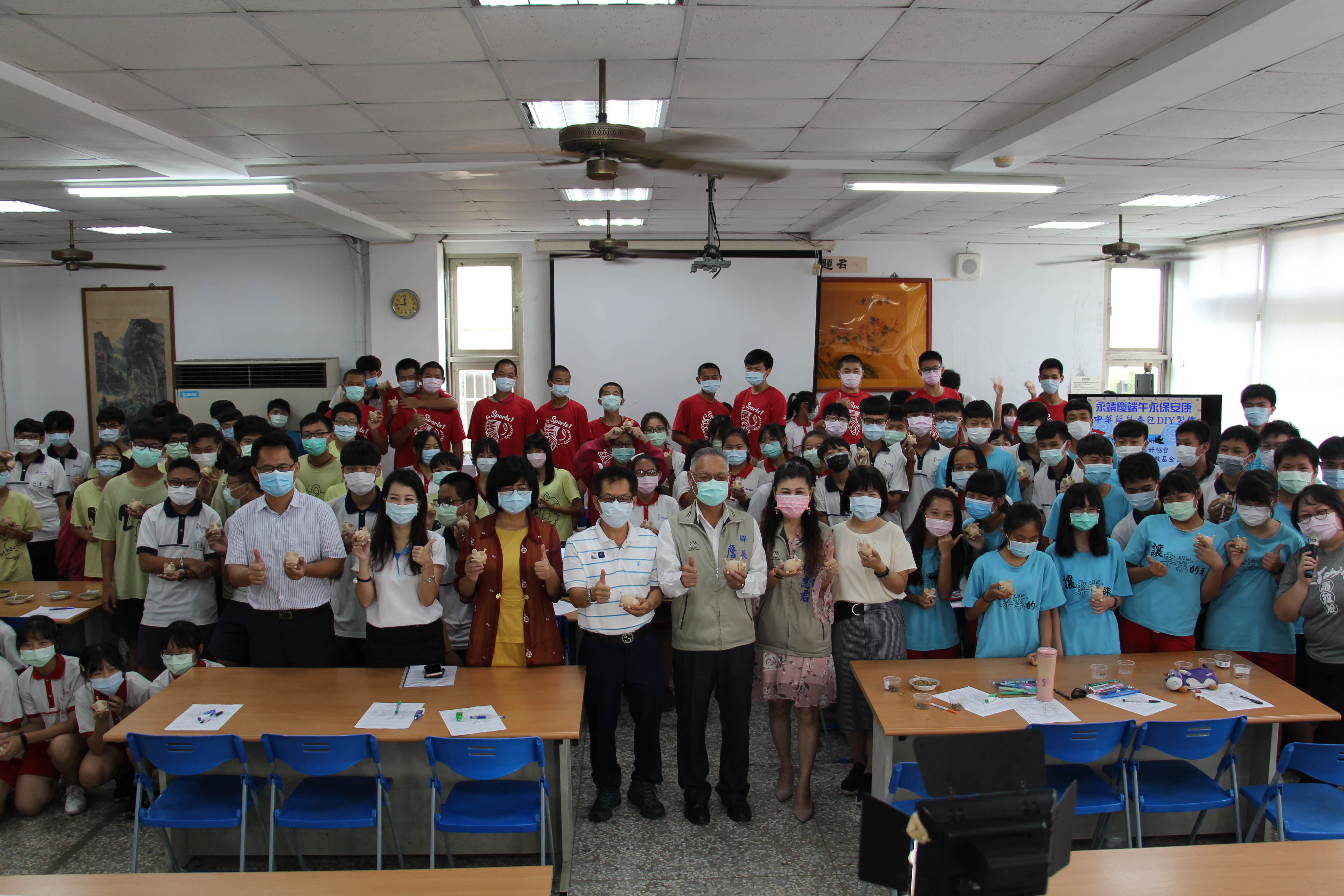 貴賓與永靖國中學生拿中藥香包鼠大合照。（頂新和德文教基金會提供）
