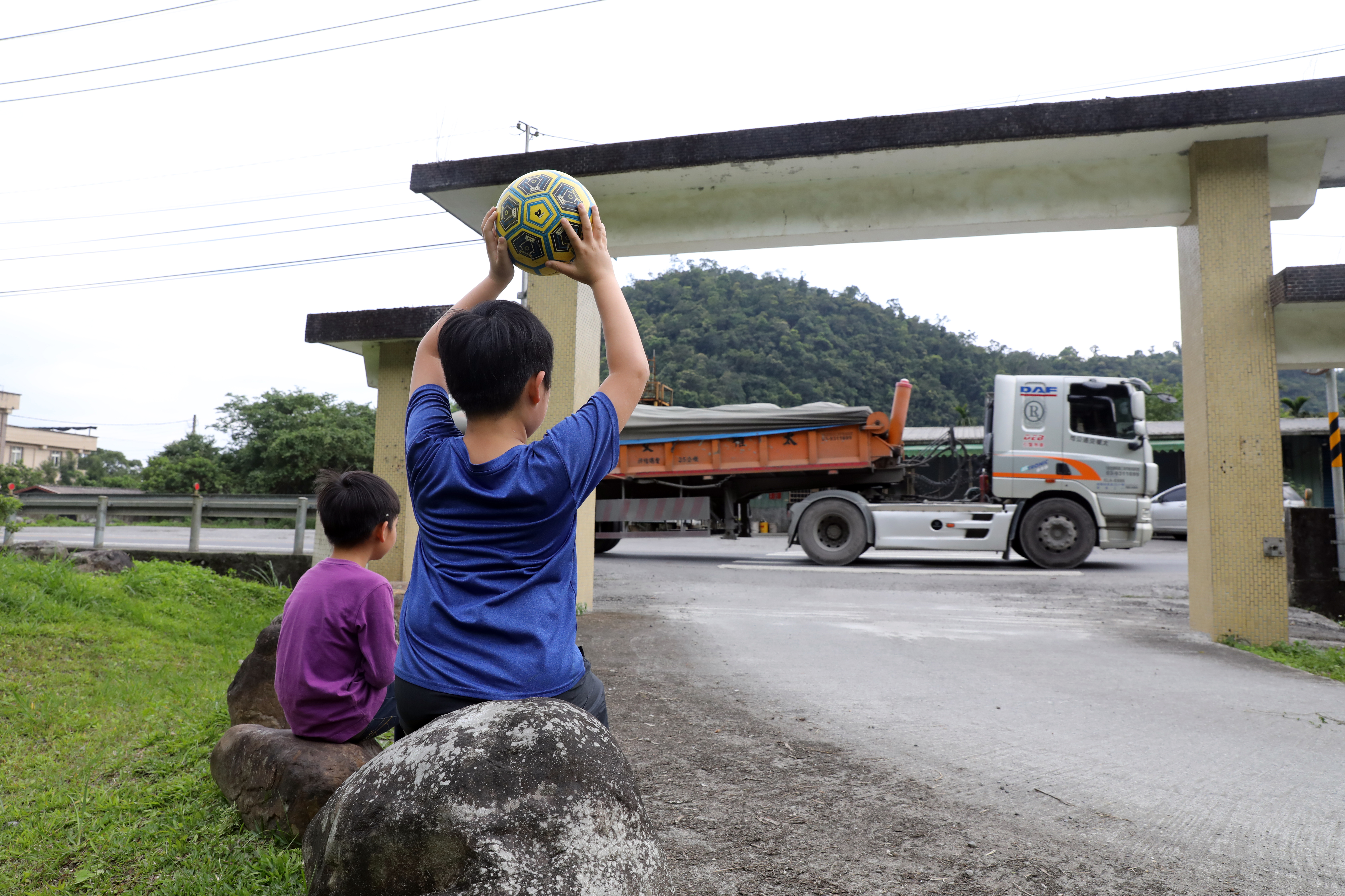 村內化育國小校門緊鄰砂石車頻繁穿越的台七線，學生上課、遊戲都擺脫不了砂石車的身影。