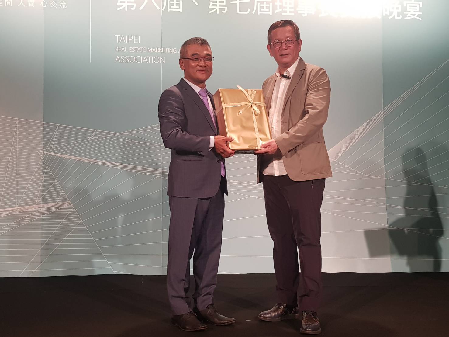 台北市不動產代銷公會12日舉辦第七屆理事長交接典禮，新任理事長由海悅國際總經理王俊傑（左）擔綱，與前任理事長、璞園建築團隊董事長李忠恕（右）互換禮物。
