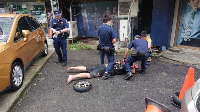 楊姓男子(右坐者)與吳姓店長(蹲者左)爆發肢體衝突,警方到場將扭打的2人分開。(翻攝畫面)