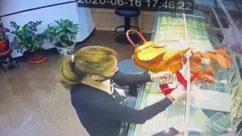 女子取出金錬子裝入包包。（翻攝畫面）