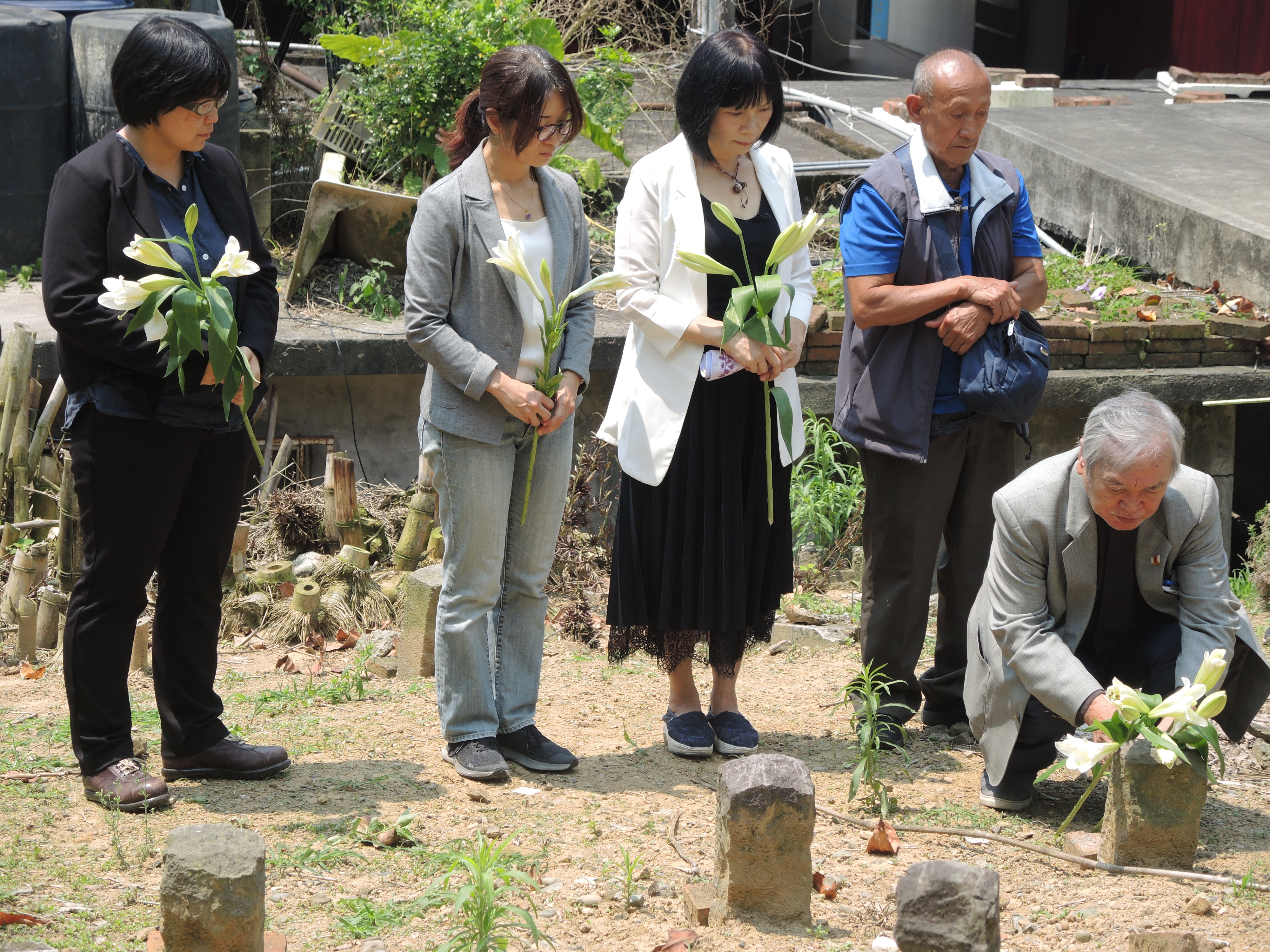 促轉會主委楊翠(左3)、彭仁郁委員(左2)、副主委葉虹靈(左1)、牧師伍錐(右1),陪同布農族原住民伍金山(右2)到六張犁政治受難者的亂葬崗,挖掘父親伍保忠的遺骨。(促轉會提供)