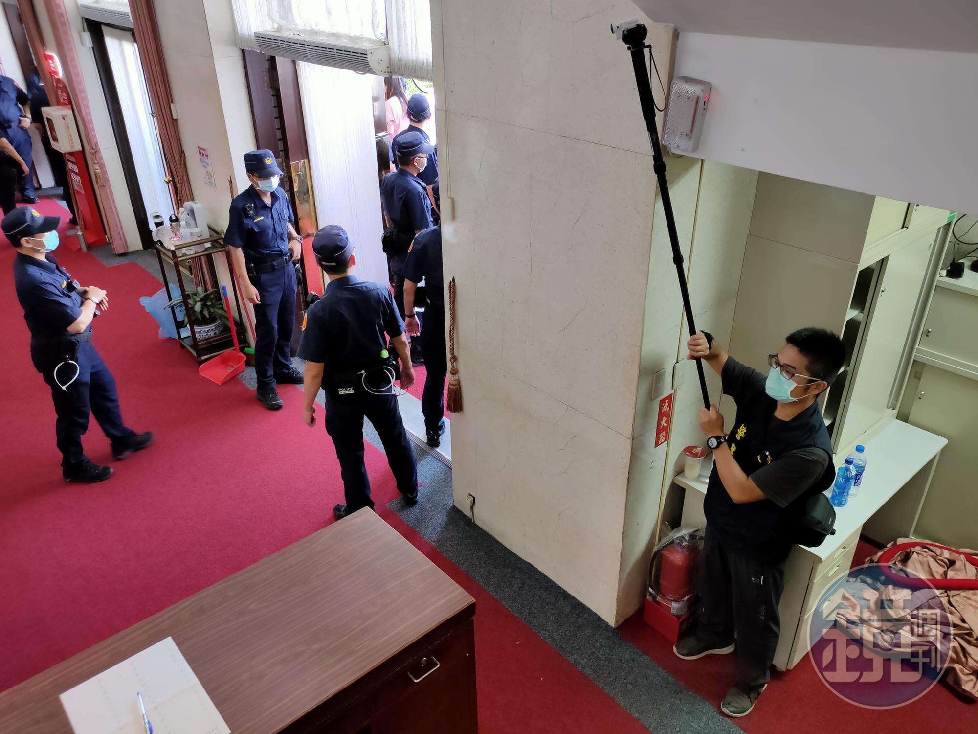 身穿警察背心的便衣刑警進入議場大門內,持攝影機蒐證。