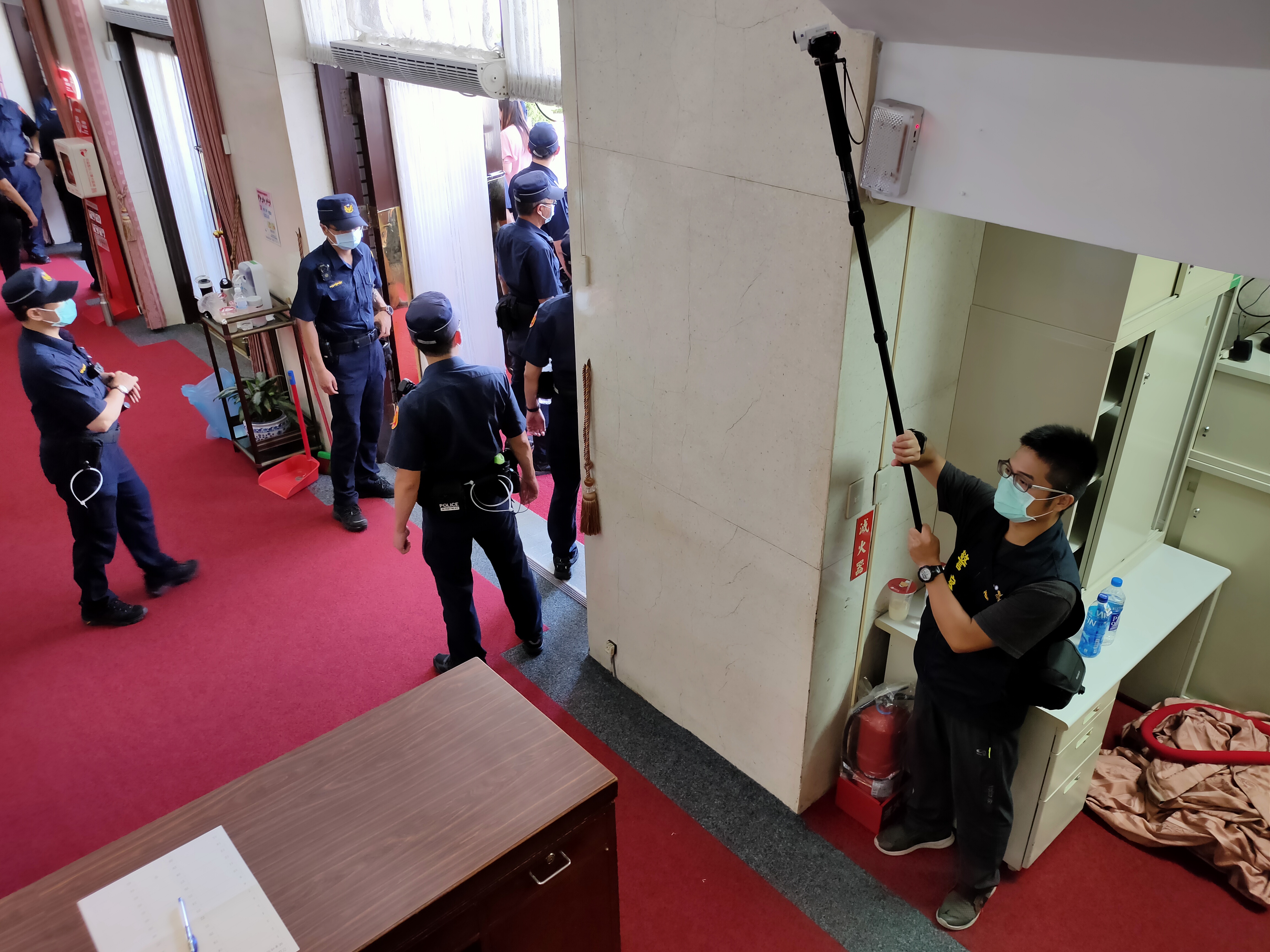 身穿警察背心的便衣刑警進入議場大門內，持攝影機蒐證。
