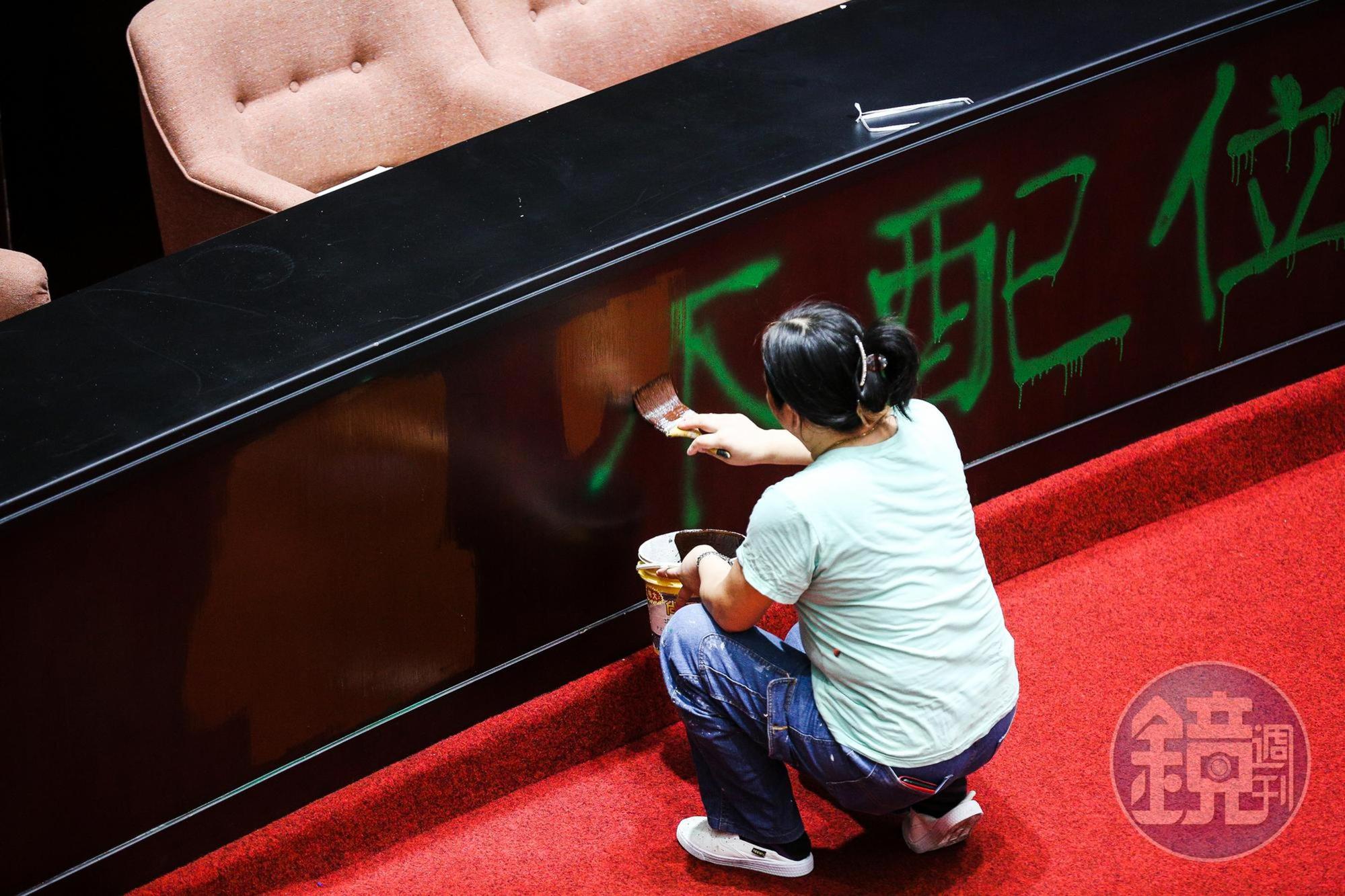 立法院工作人員將備詢台前的噴漆字樣以油漆蓋住。