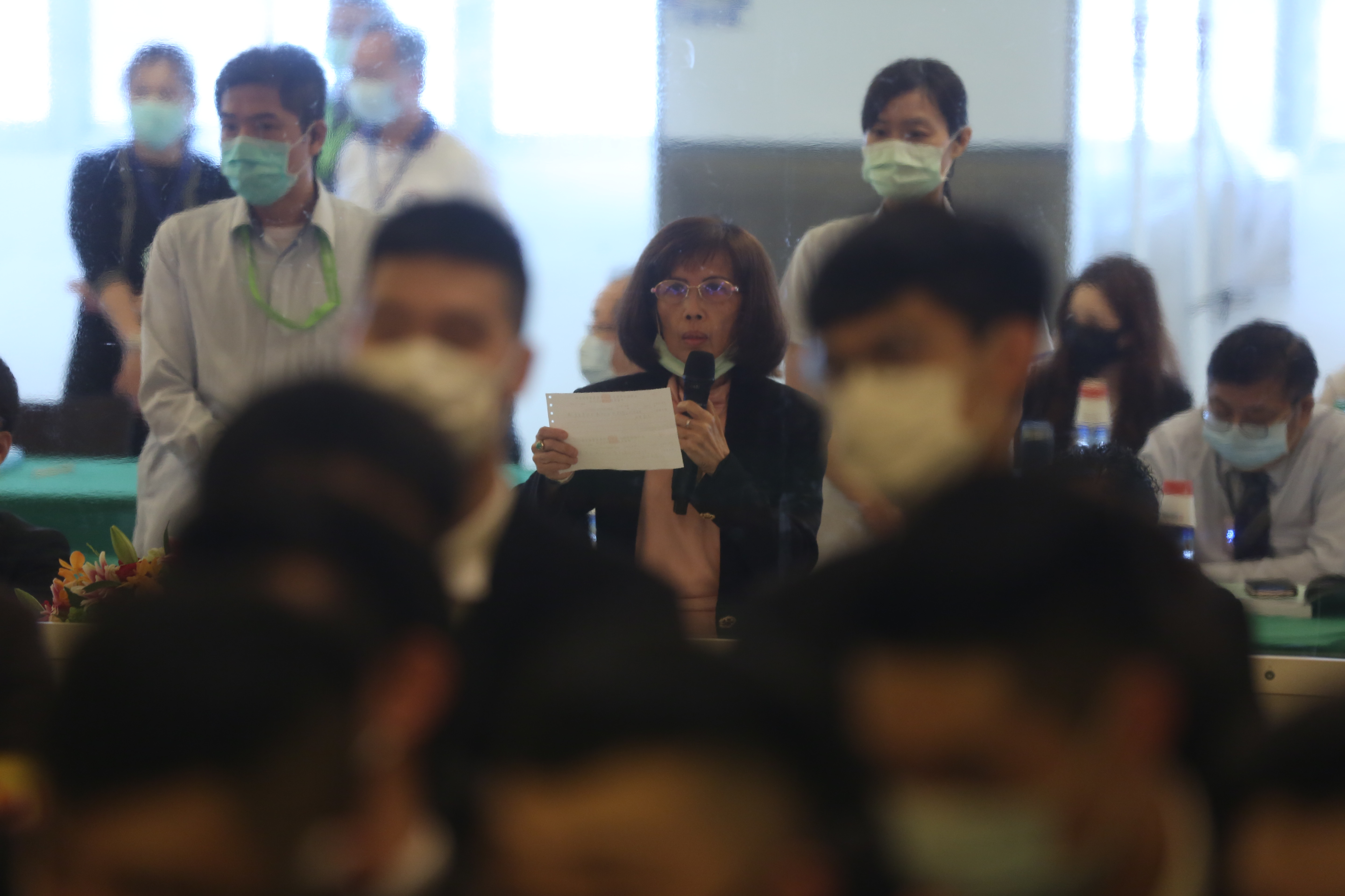 將近5個小時的股東會，董事長林郭文艷（手持麥克風者）都躲在黑衣人士組成的人牆後面。