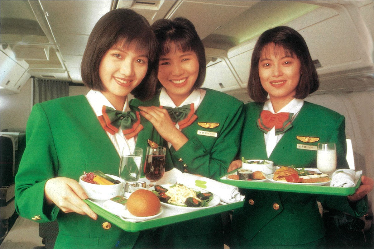 3位甜美的空服員穿著長榮第一代制服，上身的白襯衫領子繫有蝴蝶結，鮮豔的綠色外套還有墊肩。（翻攝自EVA Airways Corp. 長榮航空粉專）