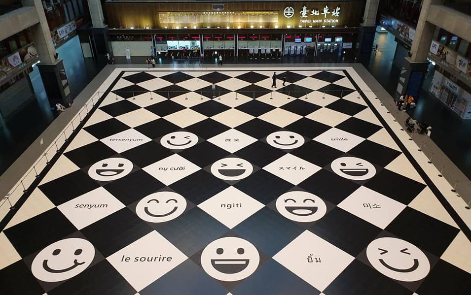 台鐵廣納各方意見，在北車大廳增加微笑地貼及寫著「微笑」的10種語文。（翻攝自交通部臺灣鐵路管理局 TRA臉書）
