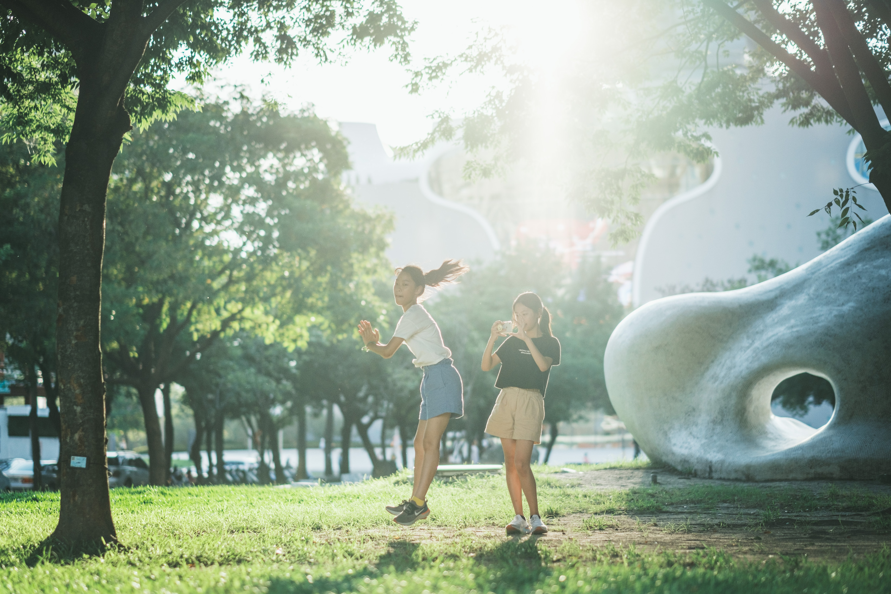 台中出差的時刻，傍晚的美好的光線如同一道聖光映照在歌劇院前的草皮上，一對青春洋溢的少女用手機捕捉俏皮的跳耀動作，不假思索的用著高速快門定住這一瞬間。