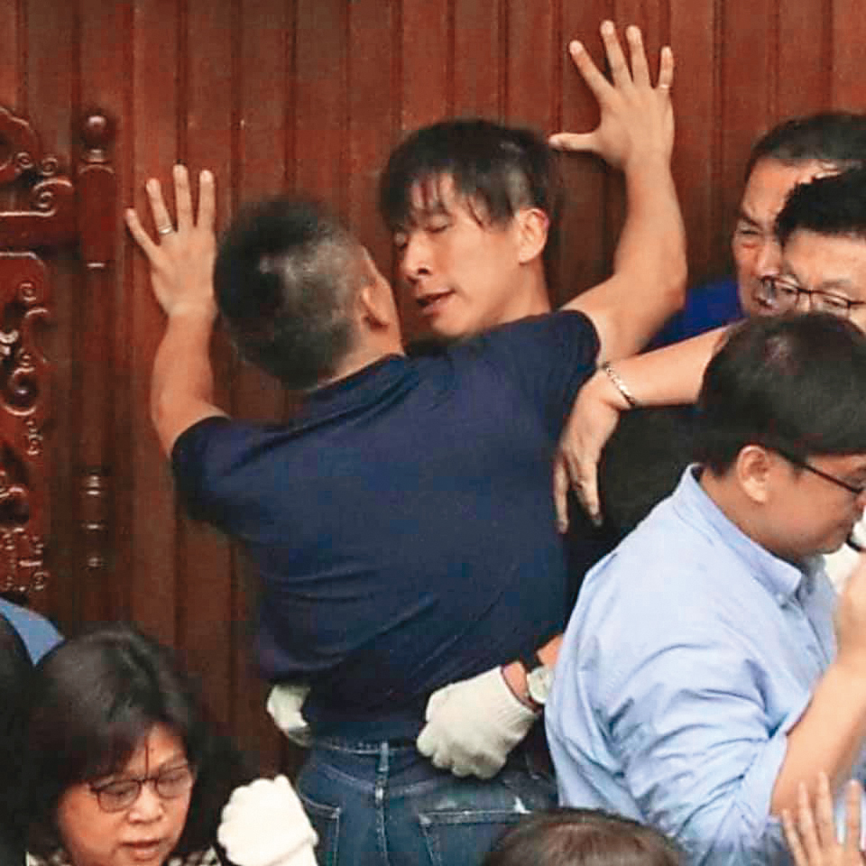 藍綠立委攻防，洪孟楷（前）「壁咚」鍾佳濱（後），   「男」分高下。（翻攝自貓與邪佞的手指臉書）