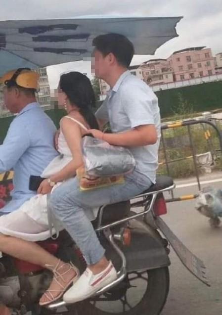 巨乳女大生表示，騎機車時，一遇路凸就會震一下，很尷尬。圖為泰國人騎機車三貼，男方出手幫女伴護胸。（翻攝自爆廢公社）