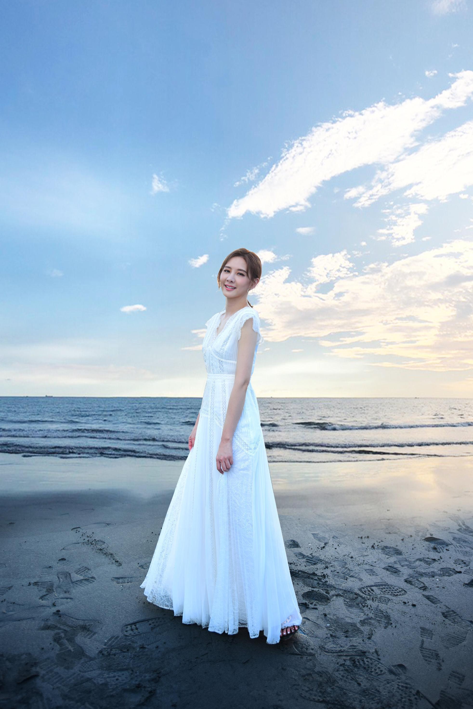 安心亞身著白色洋裝漫步沙灘,直呼想在海邊拍婚紗。(環球唱片提供)