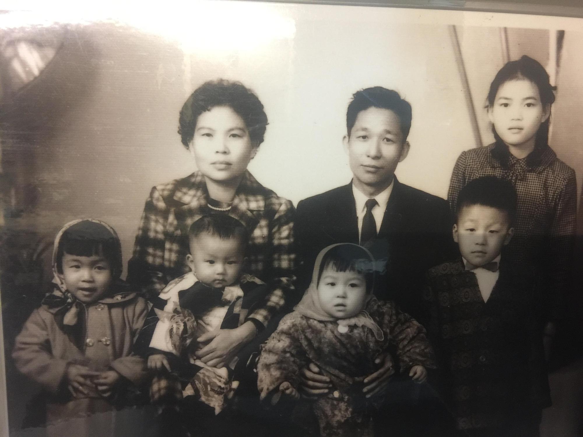 父親(後排中)是謝詠芬生命中的貴人,圖為兒時父親抱著她拍全家福。(謝詠芬提供)