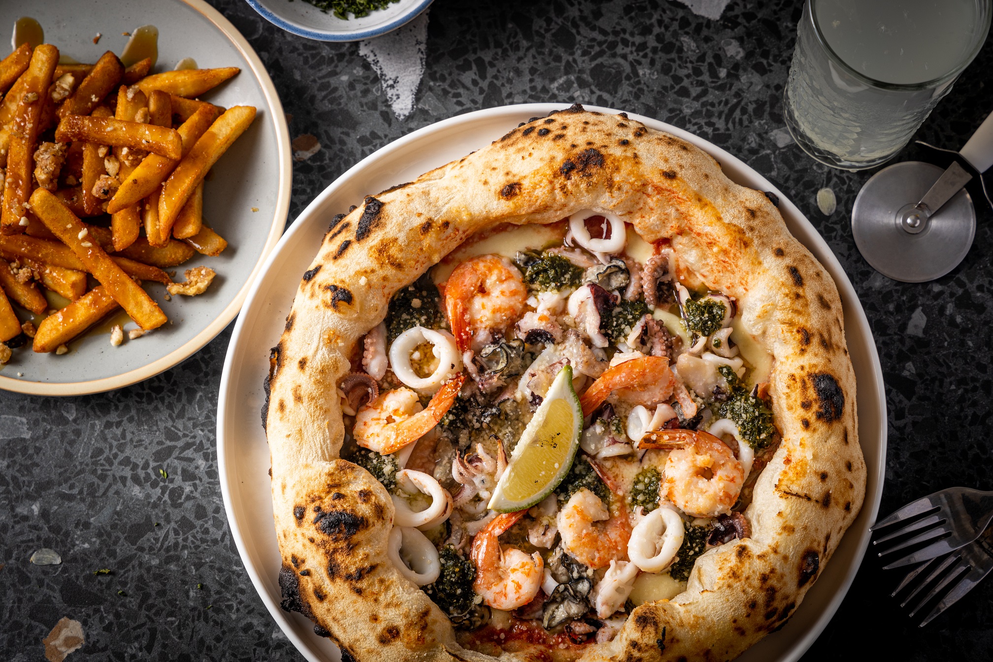 「漁市場披薩」以各種澎湖海鮮為料，一口咬下味道超鮮，配上空氣感薄皮，是台灣少見的滋味。（450元／份）