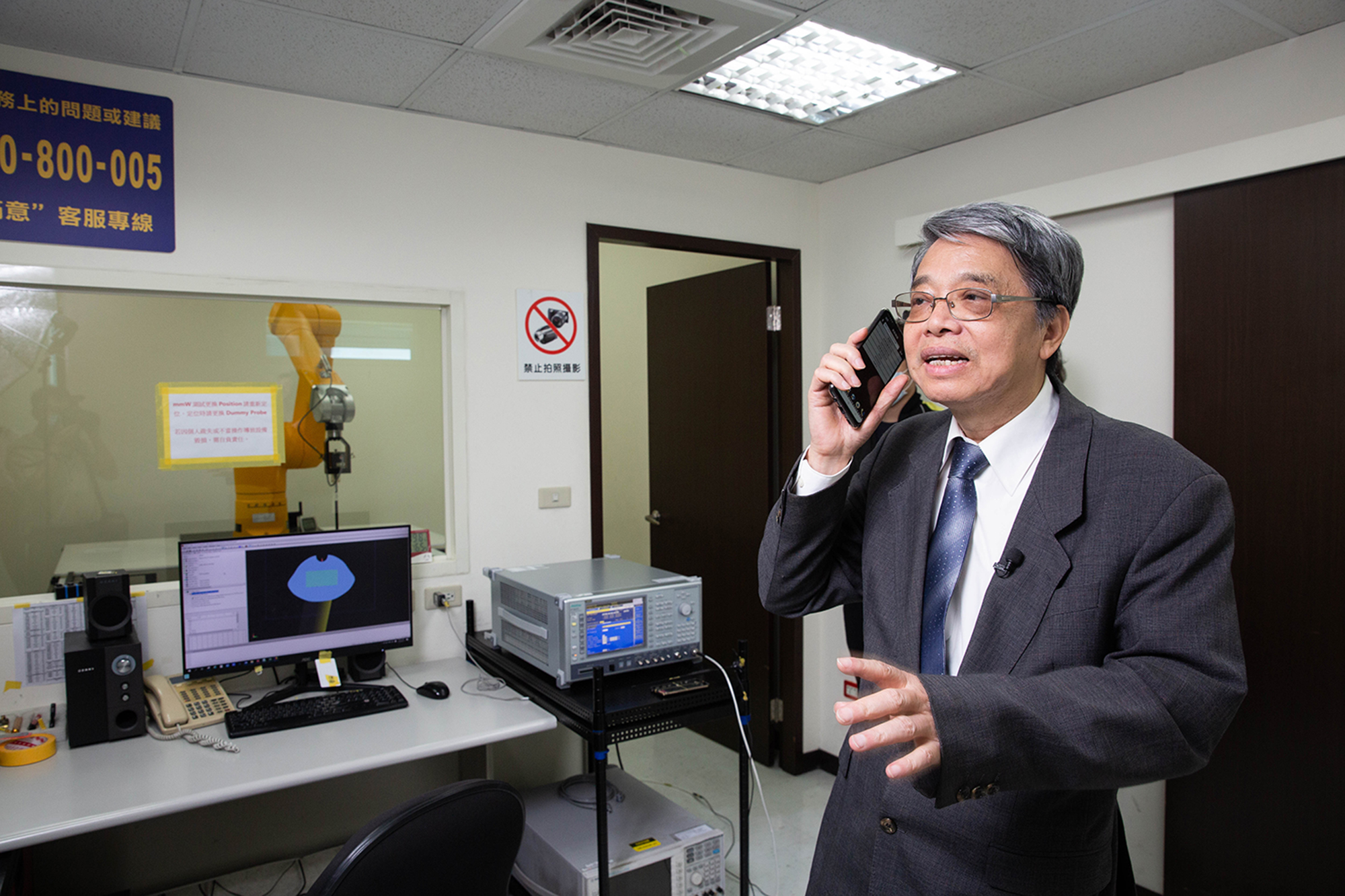 王新添拿手機示範講電話時電磁波若過強，不符法規，可能對腦部產生影響。