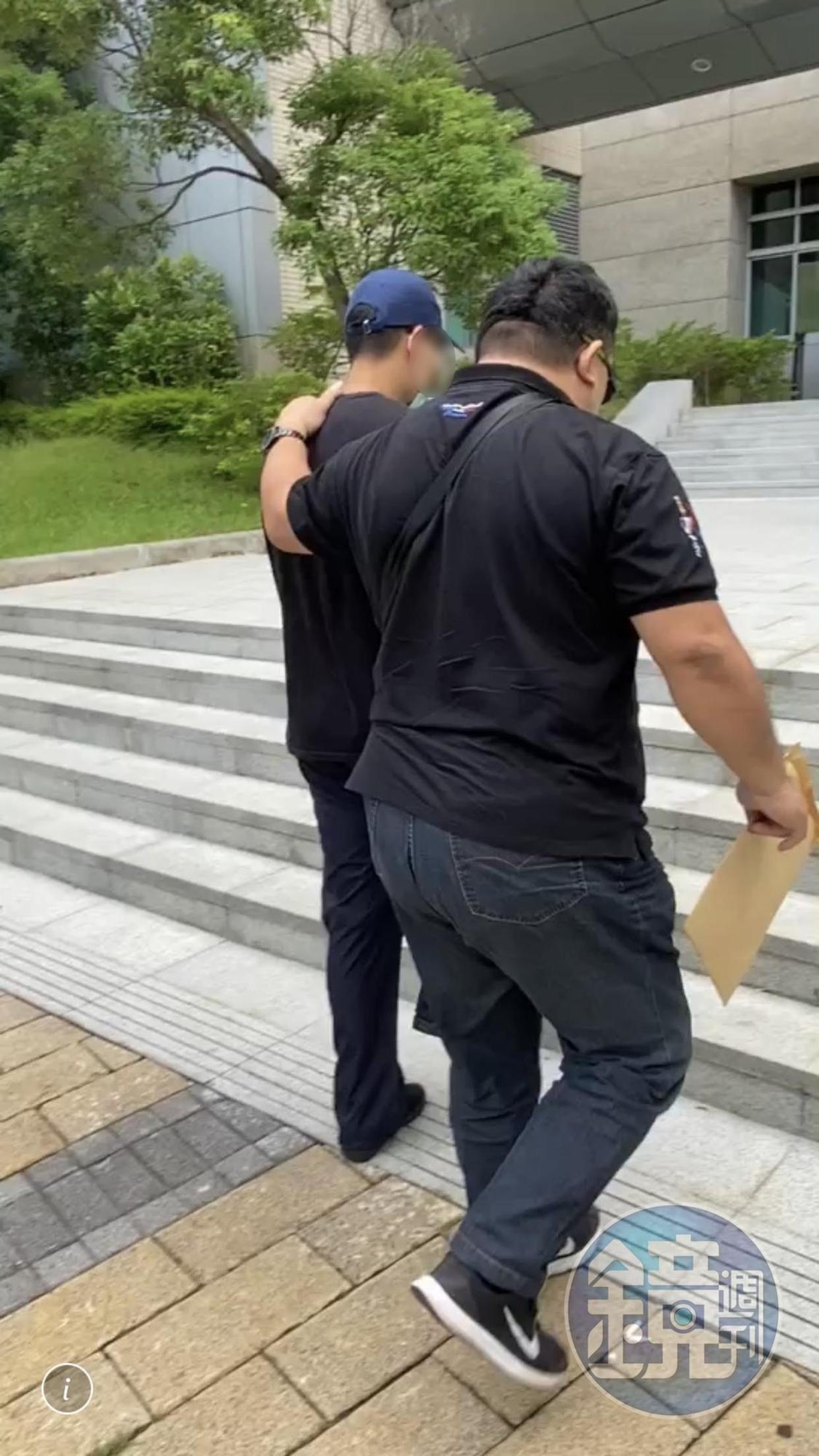 王姓網友(戴藍帽者)被警方帶回警局偵訊。(讀者提供)