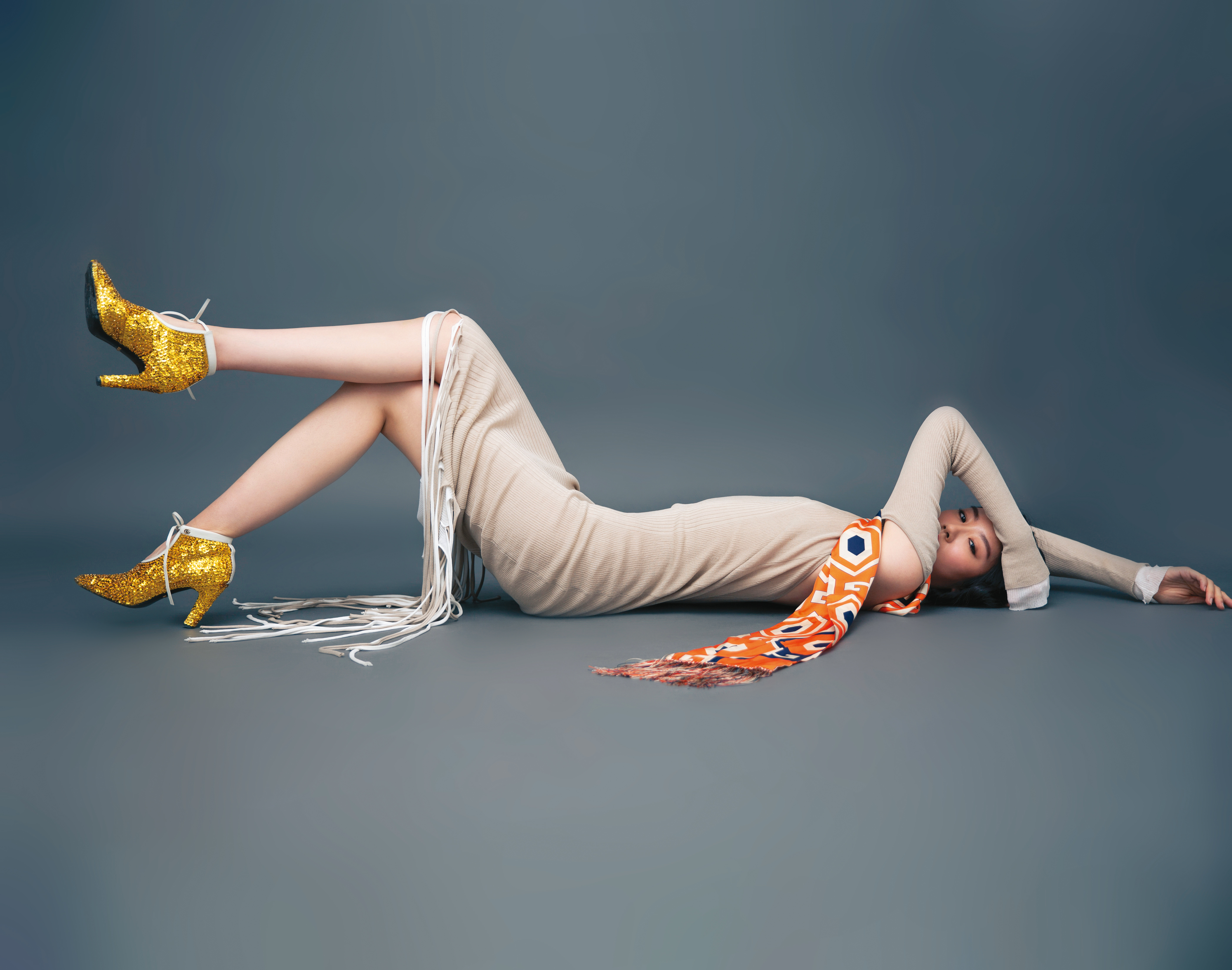 沙色高領挖背針織流蘇洋裝 NT$86,100 by BOTTEGA VENETA／藍寶石印花圍巾 NT$21,000 by GUCCI／金色亮面高跟踝靴 NT$58,700 by GUCCI