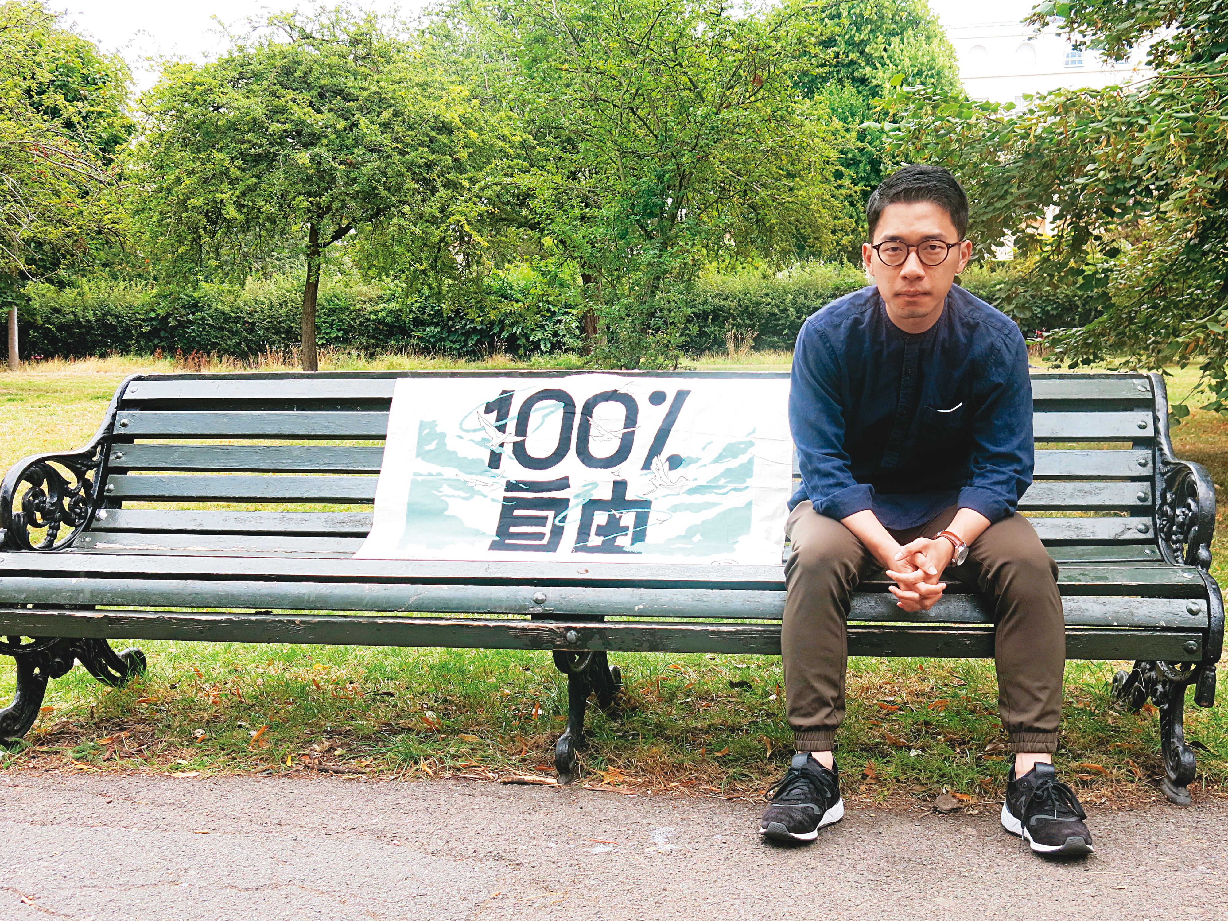 已解散的香港眾志曾引用鄭南榕「爭取100%自由」名言製作旗幟,羅冠聰如今進行國際倡議也帶著這面旗幟,香港的民主自由已是他一生的追求。(陳彥廷攝)