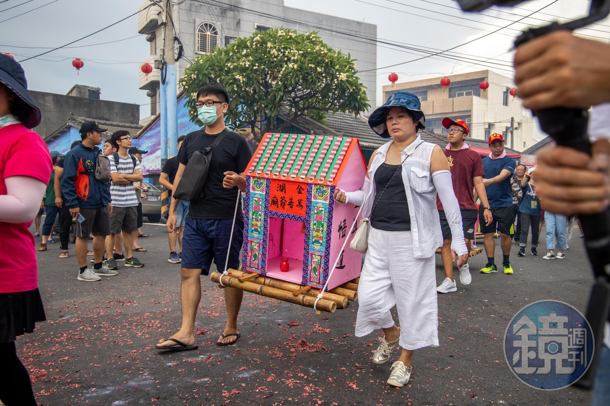 信眾抬著以竹架子與紙糊而成、造型如房子的水燈。