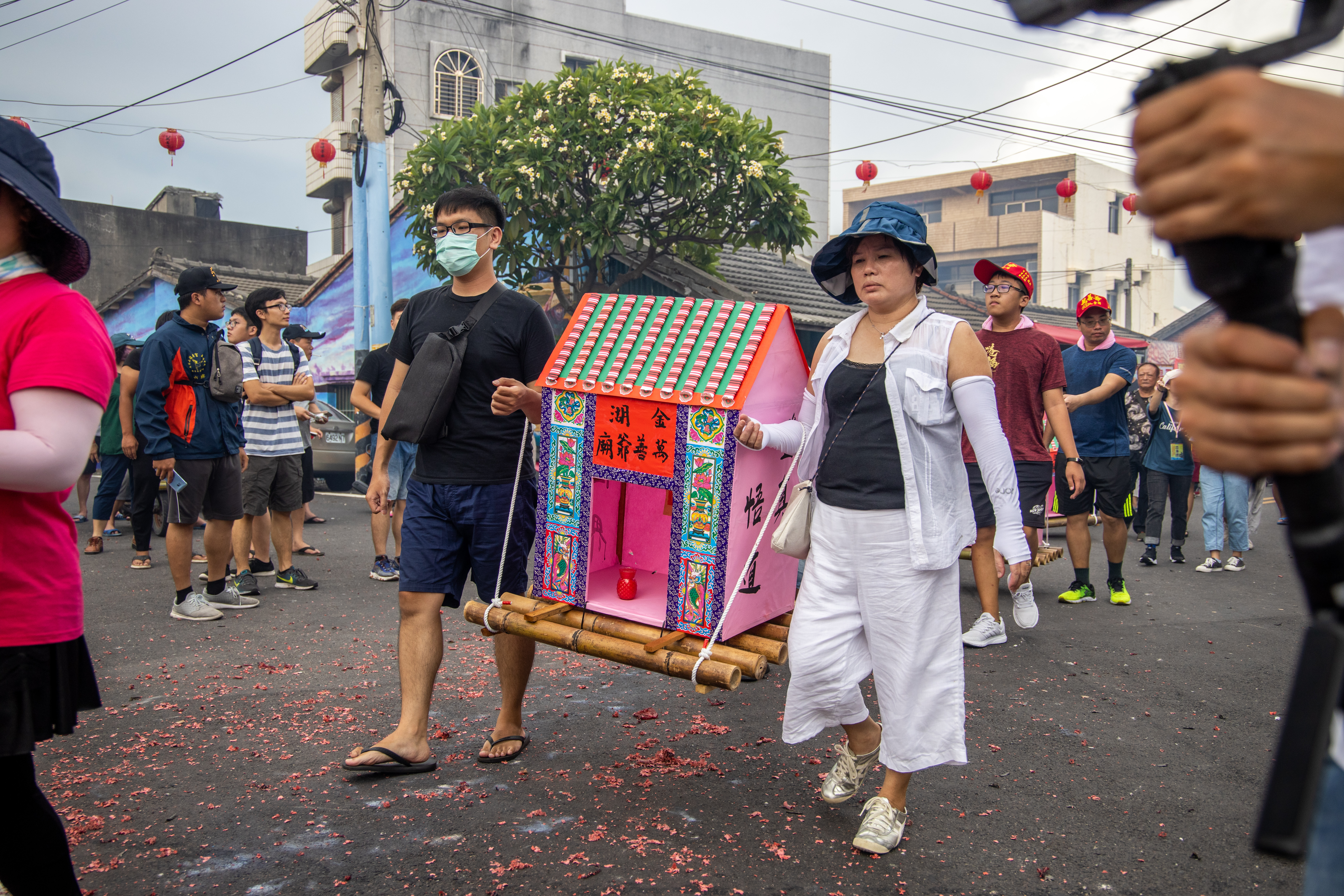 信眾抬著以竹架子與紙糊而成、造型如房子的水燈。