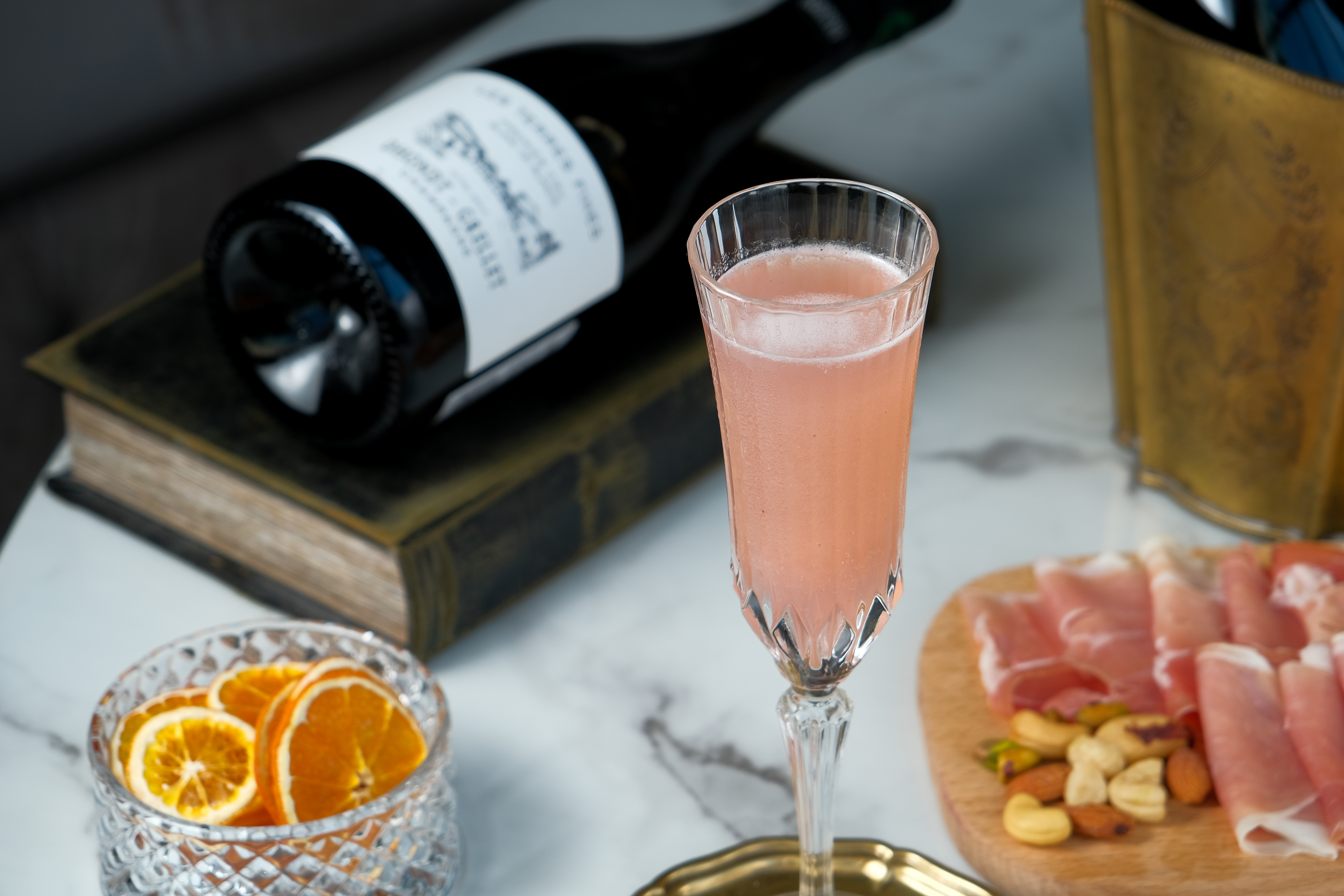 義大利經典調酒「Bellini」（中，480元／杯），在這裡以法國香檳取代義大利氣泡酒Prosecco，洋溢馥郁蜜桃香，搭配西式小食「伊比利火腿盤」（前，1,000元／份），好拍又解饞。