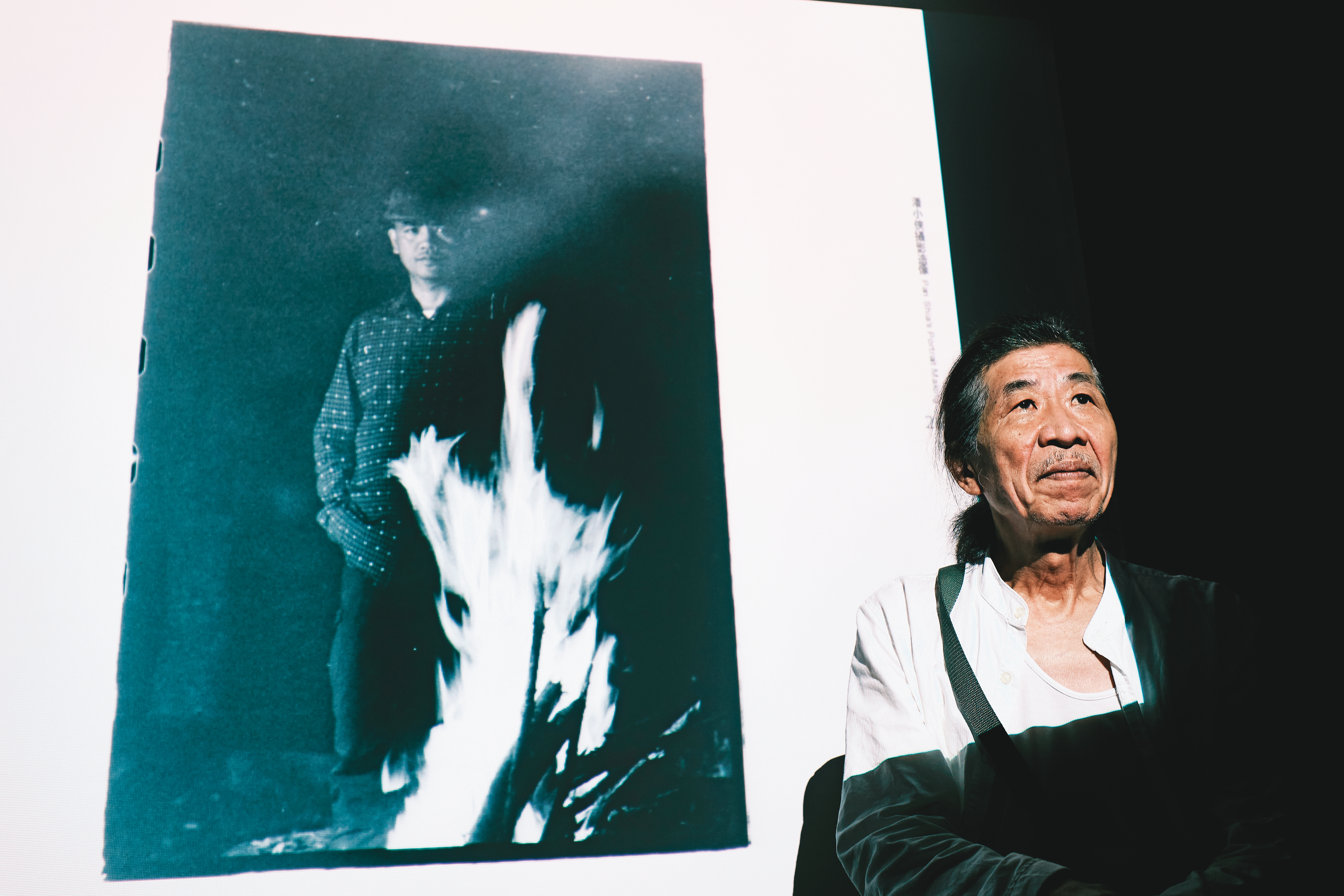 今年潘小俠出版《台灣作家一百年》，七月以原住民作家為主題開座談會。背景圖片為他拍攝的布農族作家乜寇‧索克魯曼，他說自己當天到達部落時已夜深，於是藉燃燒柴火的光線拍照。