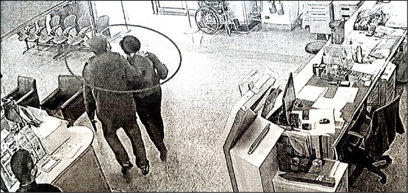 張展昭用手掐住杜女的脖子，把她架離服務櫃台往大門走去。（讀者提供）