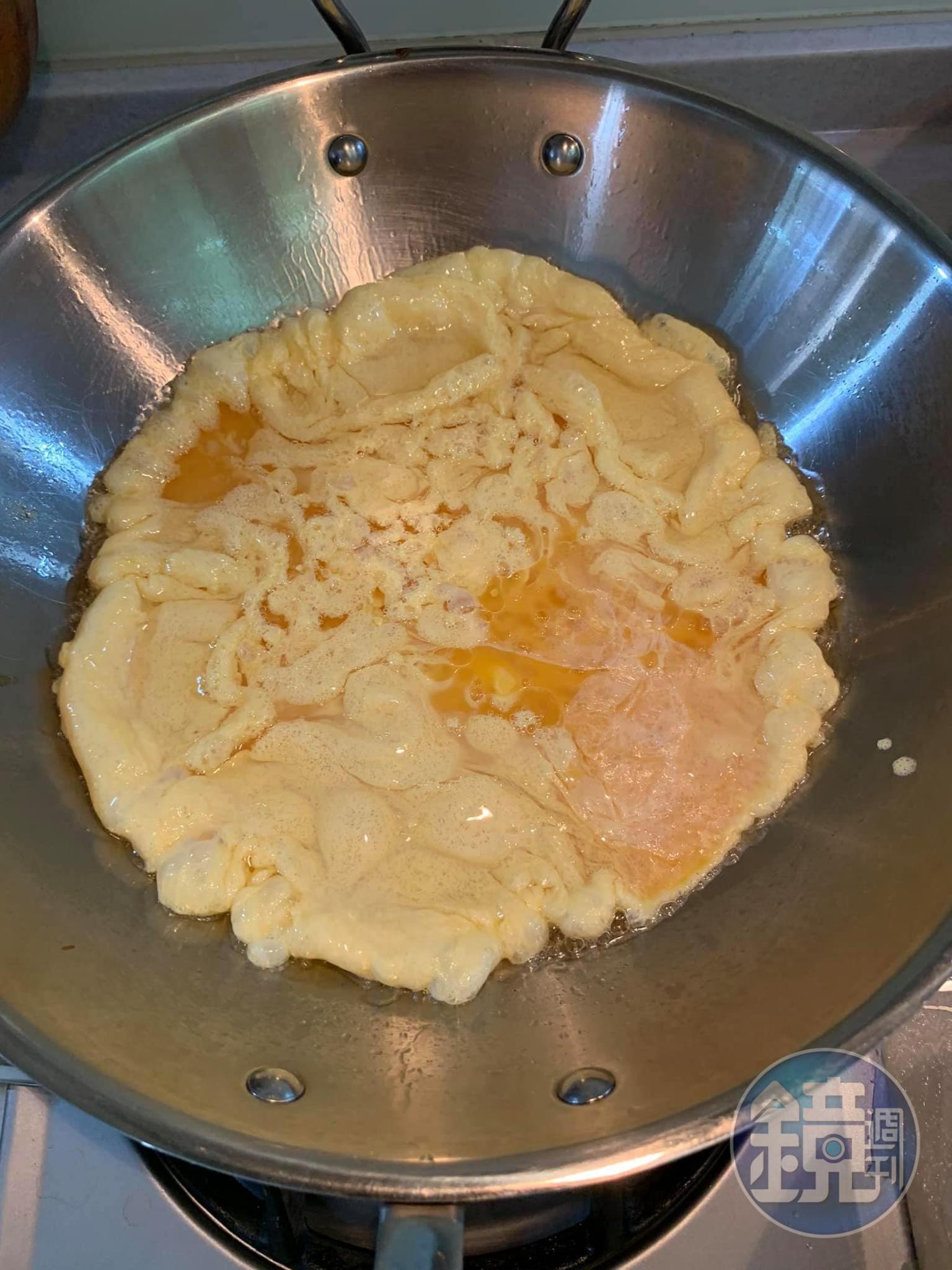 將調好的蛋汁倒入熱鍋中，用長筷略微攪拌。