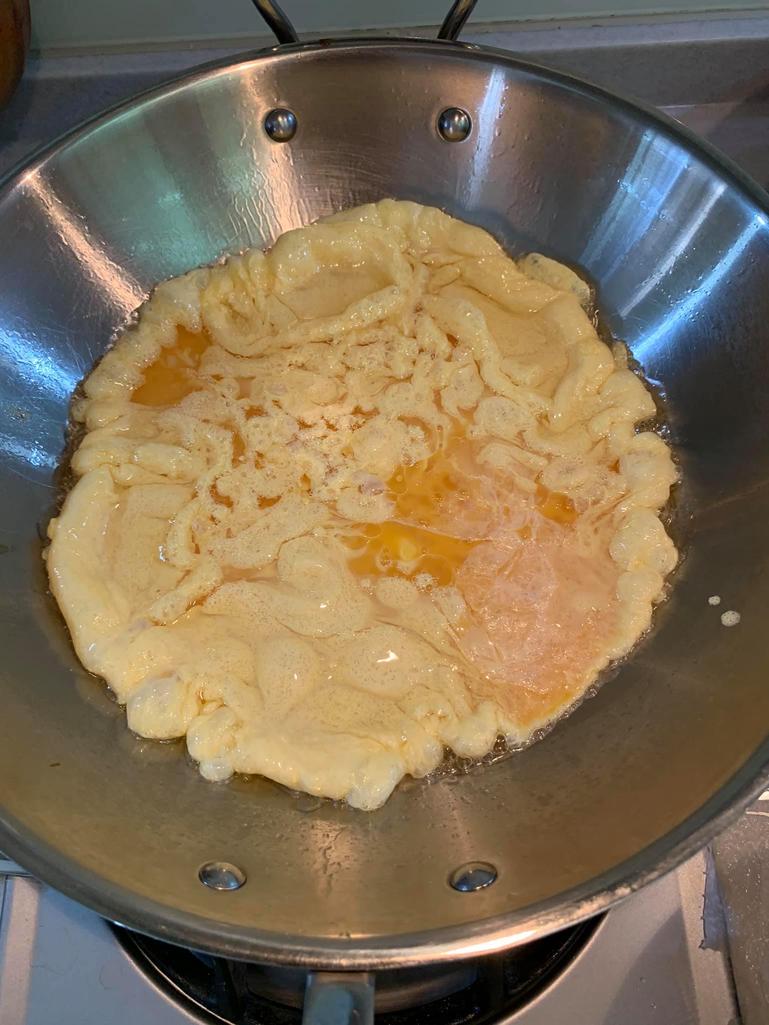 將調好的蛋汁倒入熱鍋中，用長筷略微攪拌。