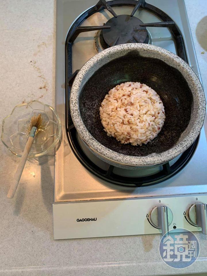 石鍋內部刷上香麻油，倒入一碗飯，鋪平。